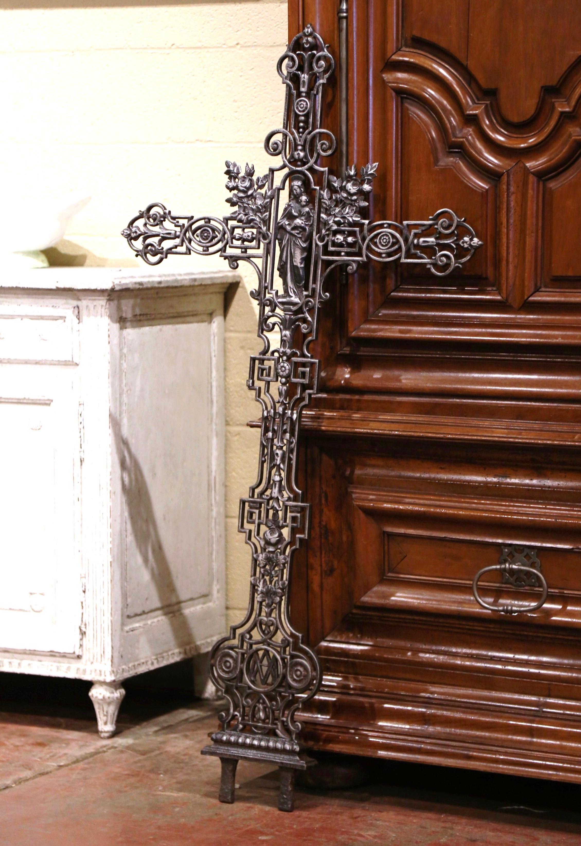 This beautiful, antique cross was crafted in France, circa 1870. The large iron piece is decorated with floral and leaf motifs in high relief all-over the cross, and embellished with a sculpture of Madonna holding the Child. The tall religious