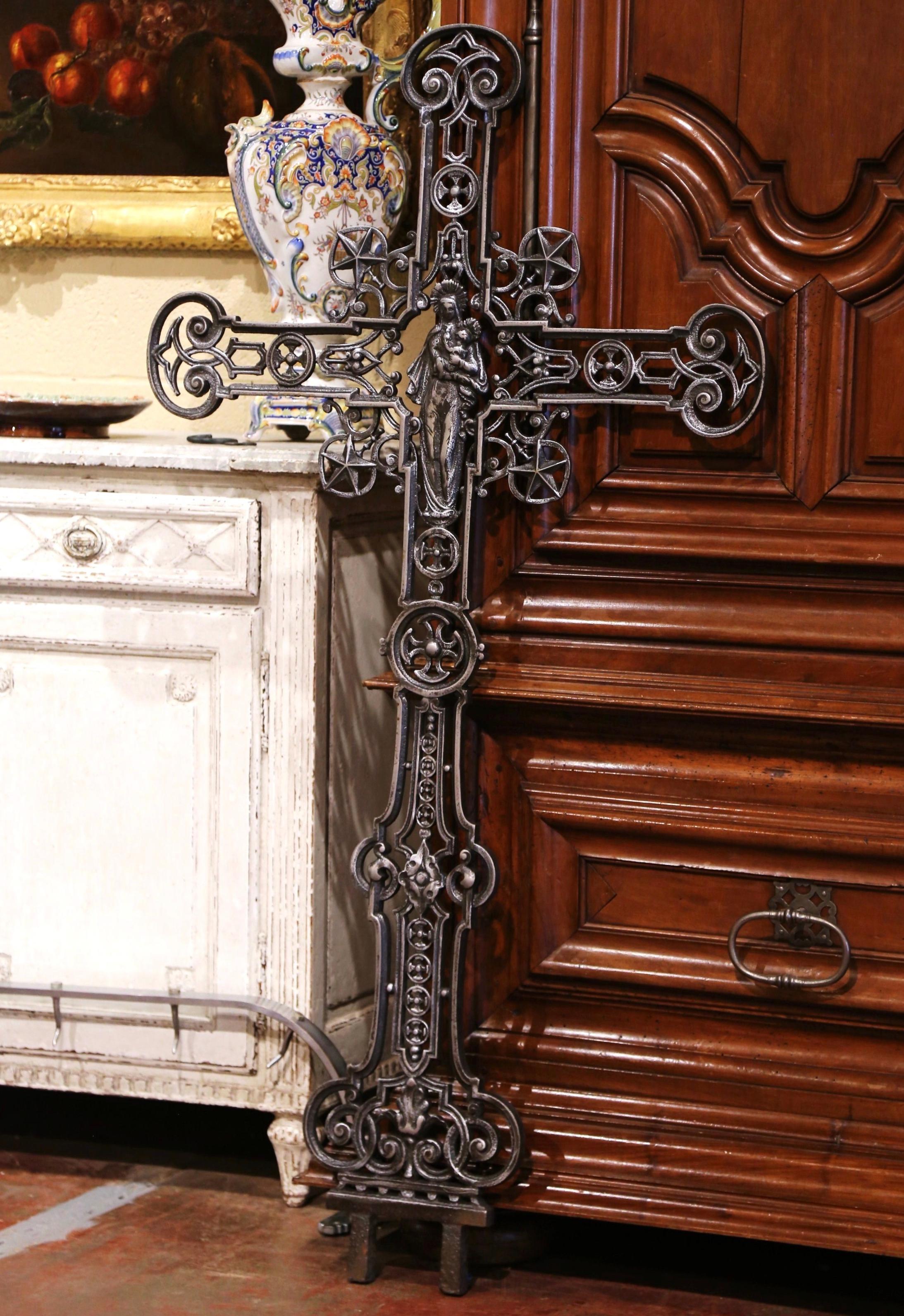 This beautiful antique cross was crafted in France, circa 1870. The large iron piece decorated with star and scroll motifs, is embellished in the center with a sculpture of Madonna holding the Child. The tall religious cross is in excellent