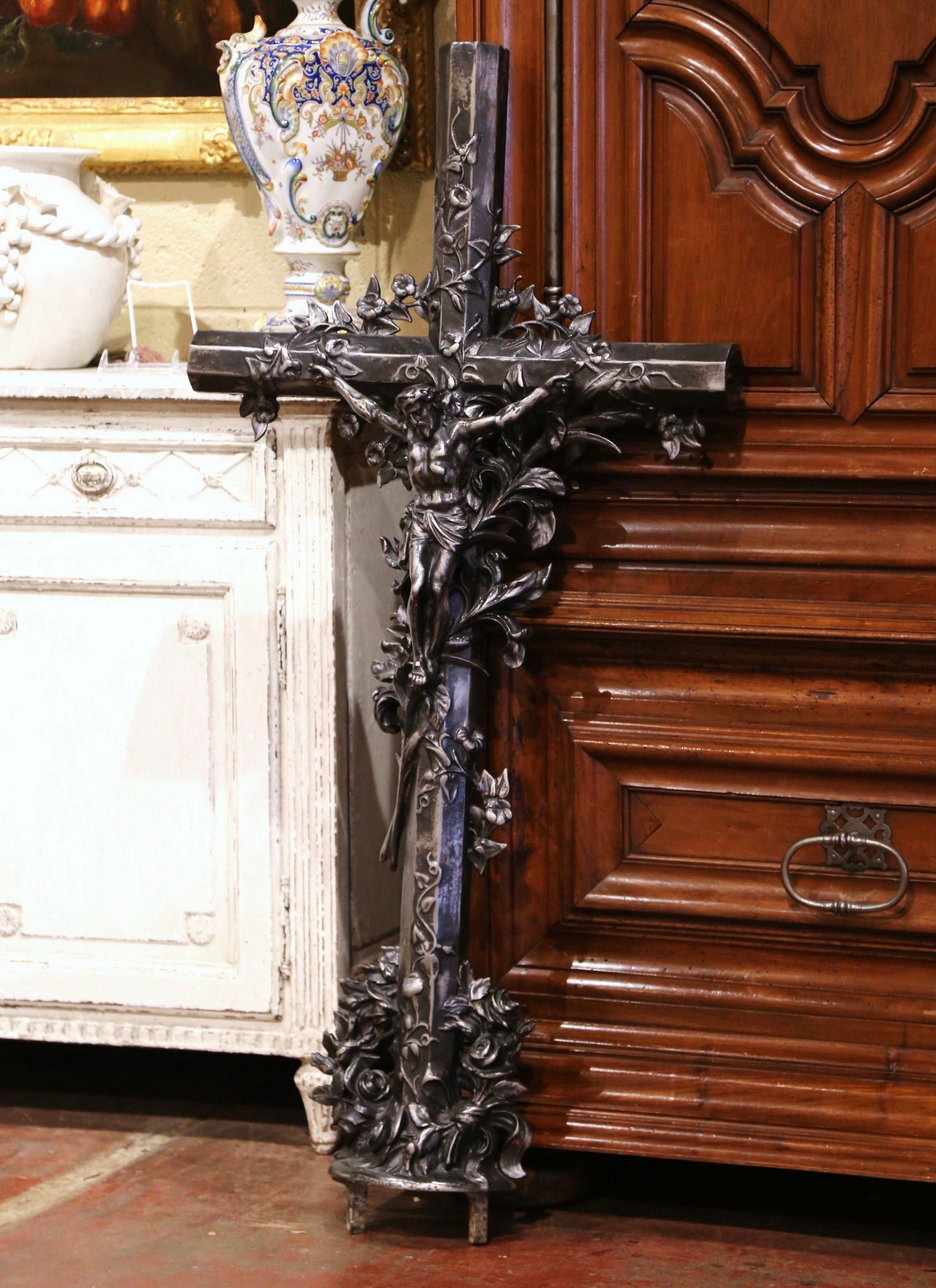 This beautiful, antique cross was crafted in France, circa 1860. The large iron piece rests on an oval base, and features our Lord nailed on the cross and is decorated with vine motifs and rose garlands in high relief all throughout. The Classic