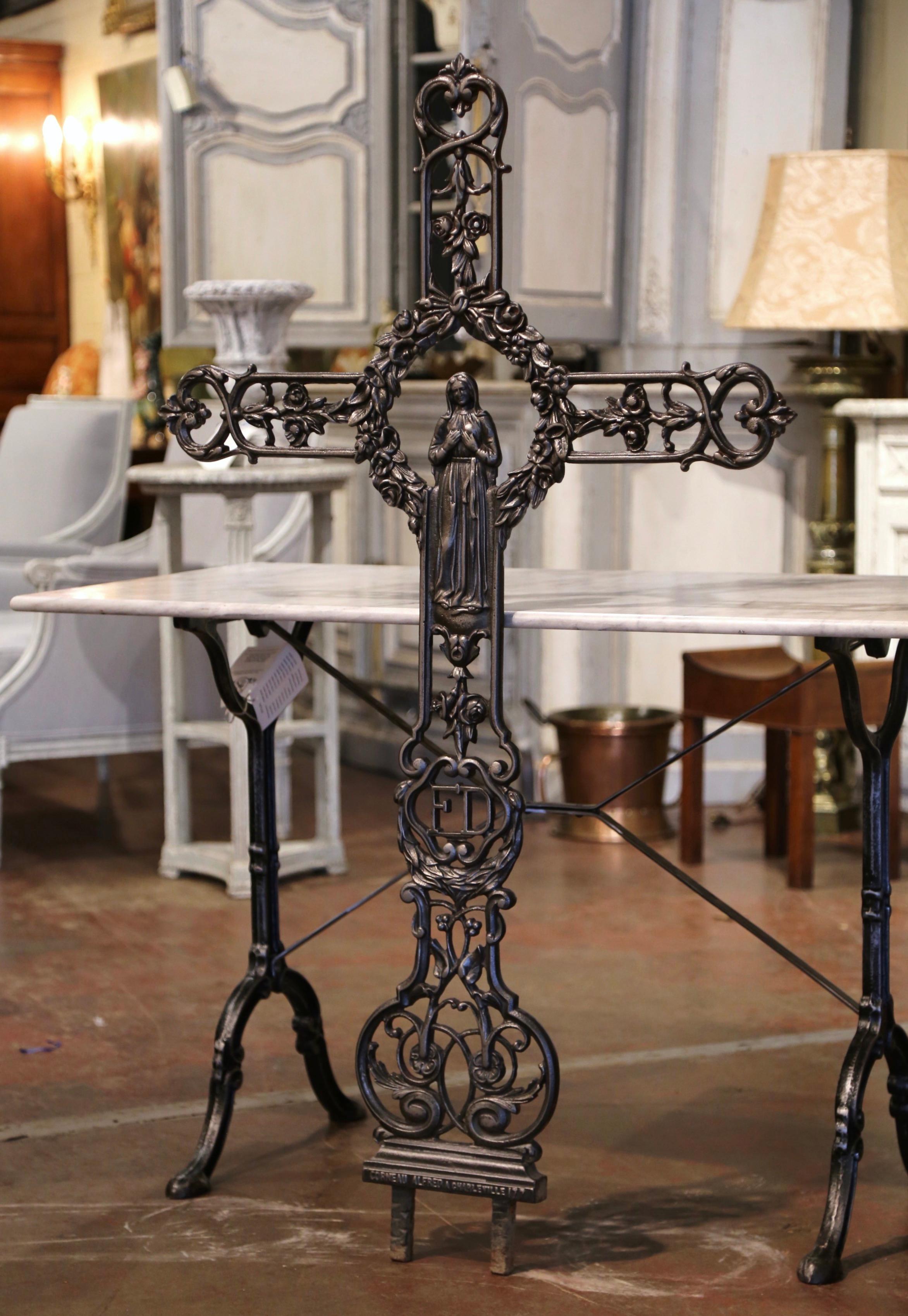 This beautiful antique cross was crafted in France, circa 1870. The large iron religious item decorated with scroll and floral motifs is embellished with the Virgin Mary in prayers at the center, surrounded by a beautifully crafted wreath. The tall