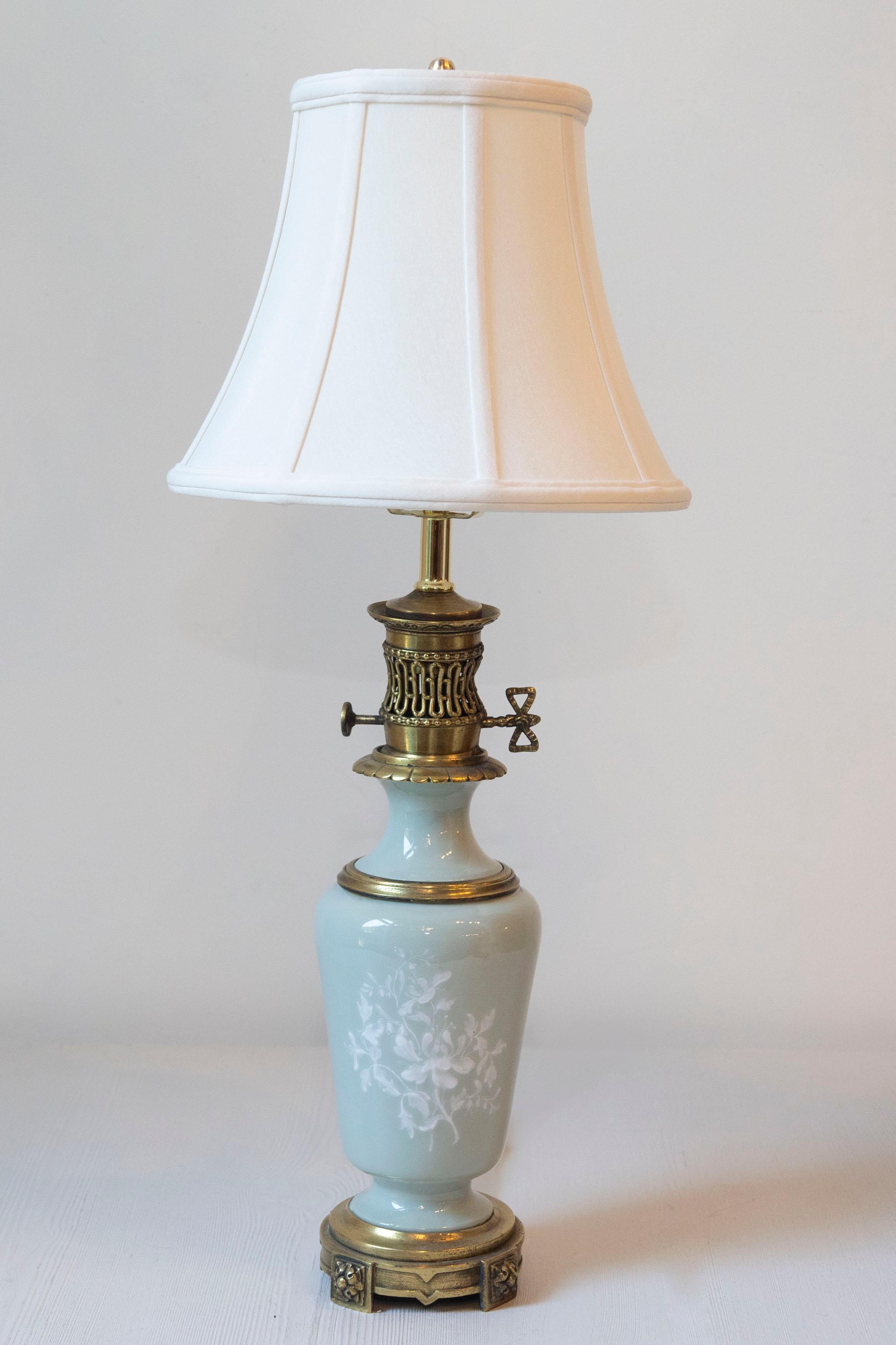 Diese französische Lampe aus dem 19. Jahrhundert ist ein beeindruckendes Beispiel für klassische Eleganz und raffinierte Handwerkskunst. Der Sockel ist aus hochwertigem Porzellan gefertigt und zeigt ein zartes, handgemaltes Blumenmotiv in zarten