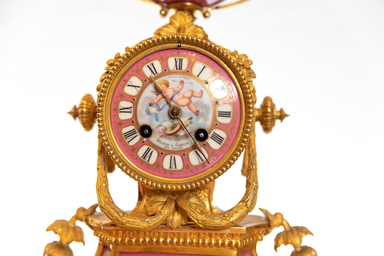 A late 19th century 8 day hour and half hour striking the hours on a single bell mantel clock. With pink porcelain hand painted panels depicting romance and lovers. The enamel dial is signed by the original retailers Wilson & Gandar of 392 the