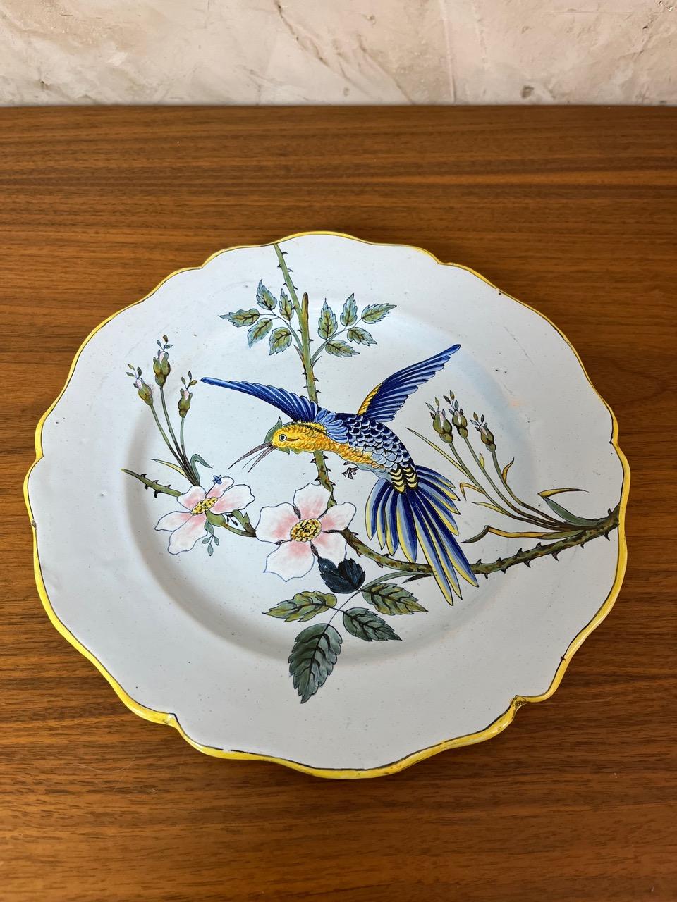 Scalloped dinner plate from the renowned French Porquier-Beau faience factory, dating from 1880. Its charm lies in the vibrant yellow rim and the finely executed decoration featuring a delicate hummingbird among wild roses, set within a rich
