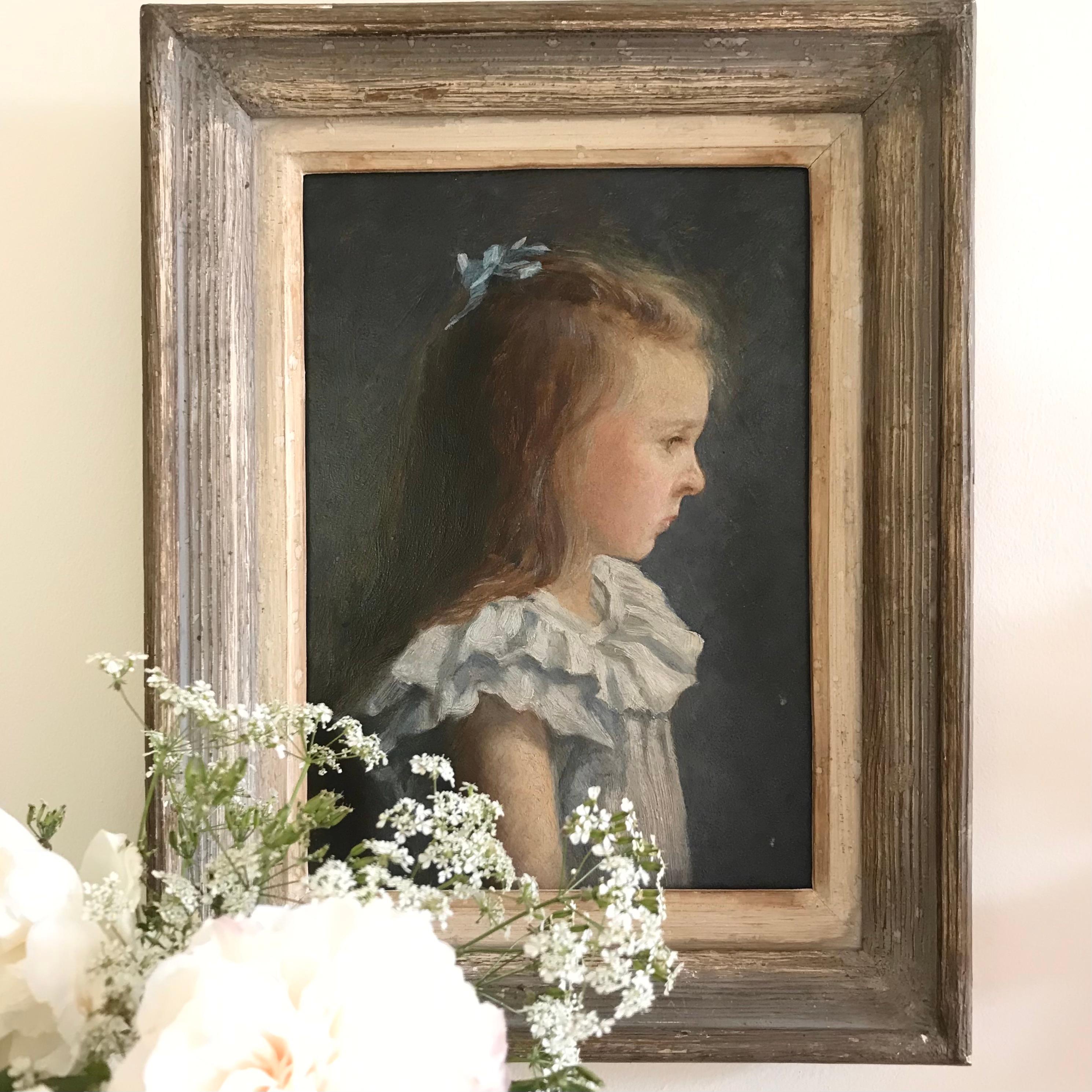 A very charming late 19th century oil on board portrait of a young French girl aged five and a half years and dated 1893 with a thoughtful expression and wearing a pale blue dress - in a subtle painted French frame with lighter painted internal slip