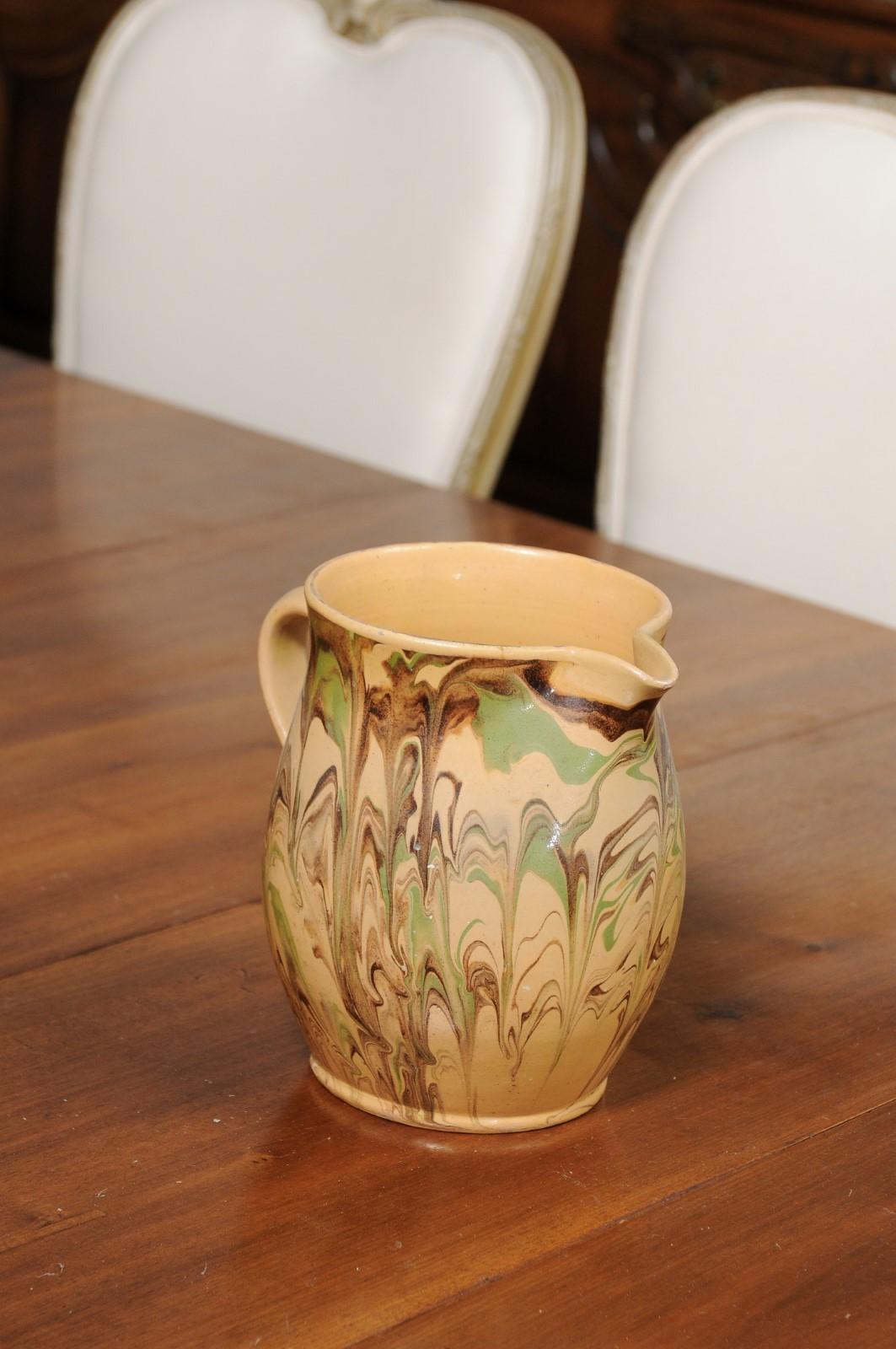 A French pottery pitcher from the 19th century, with green and brown marble style design. Created in France during the 19th century, this pottery pitcher features a yellow ground accented with a lovely dripping décor and green and brown tones