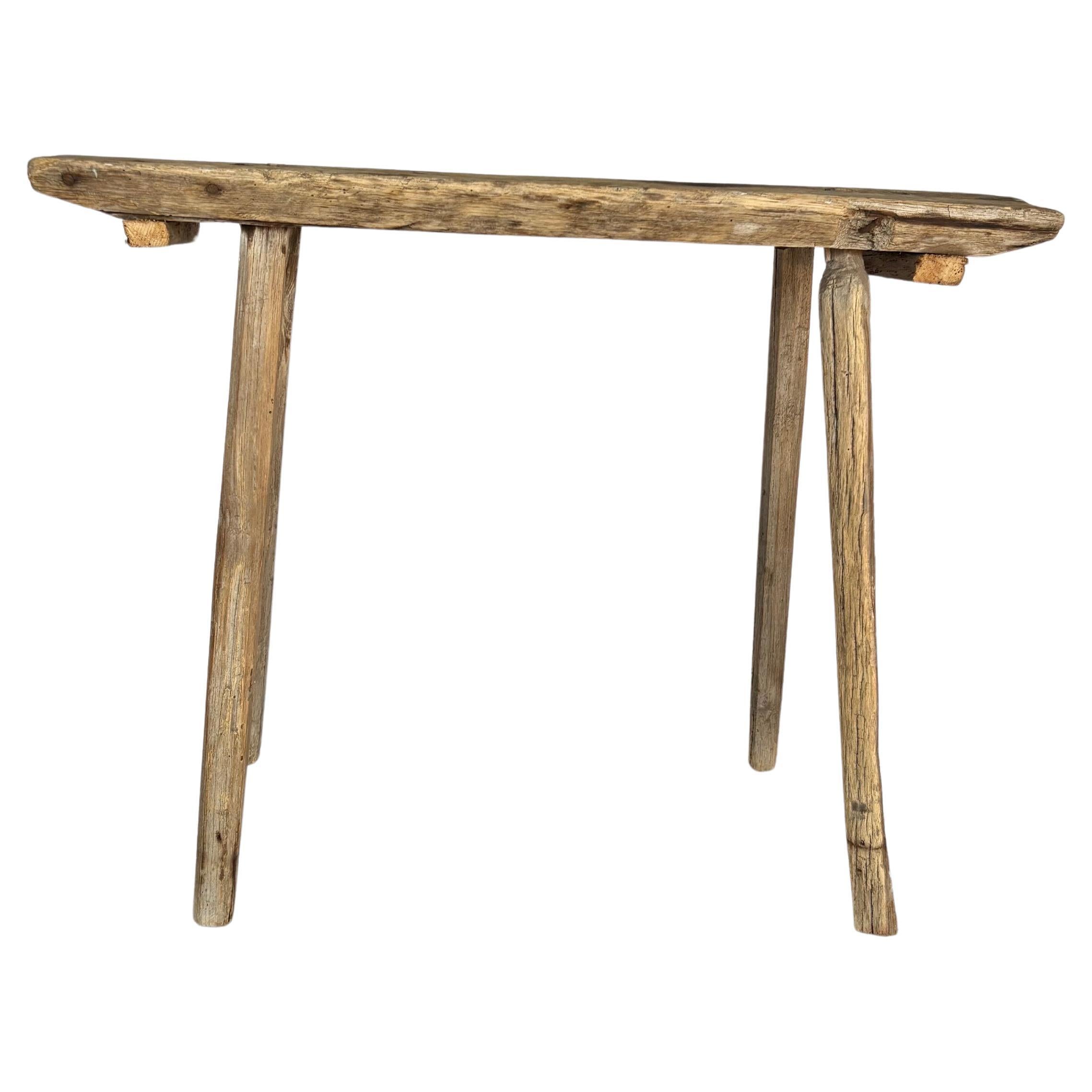 Trouvé dans le sud de la France, ce banc en bois primitif du XIXe siècle a été fabriqué à la main à la fin des années 1800. Le meuble présente un plateau en bois massif reposant sur quatre pieds évasés. Ce banc peut également servir de petite table