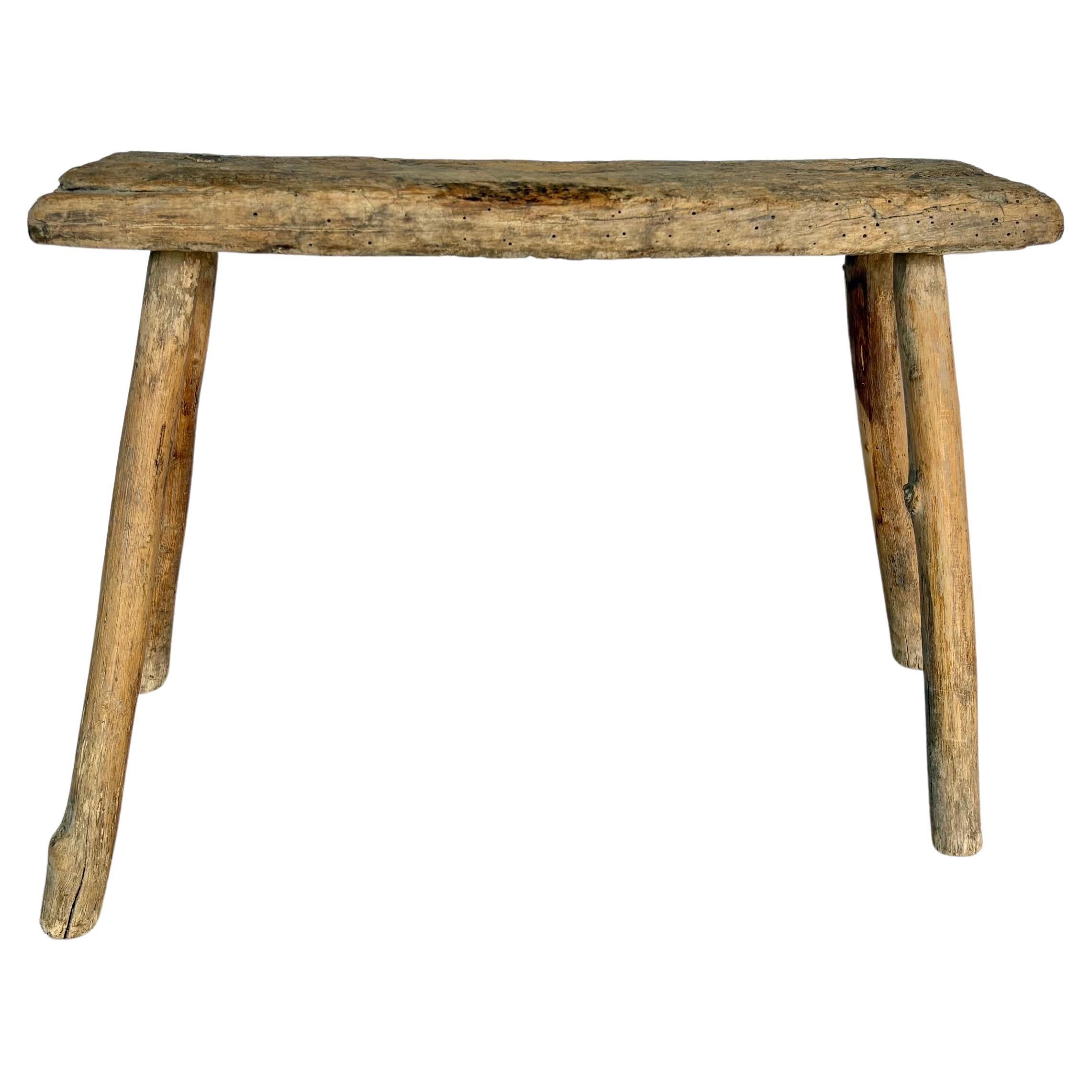 Diese in Südfrankreich gefundene primitive Holzbank aus dem 19. Jahrhundert wurde in den späten 1800er Jahren handgefertigt. Das Stück besteht aus einer massiven Bohlenplatte, die auf vier gespreizten Beinen ruht. Diese Bank kann auch als kleiner