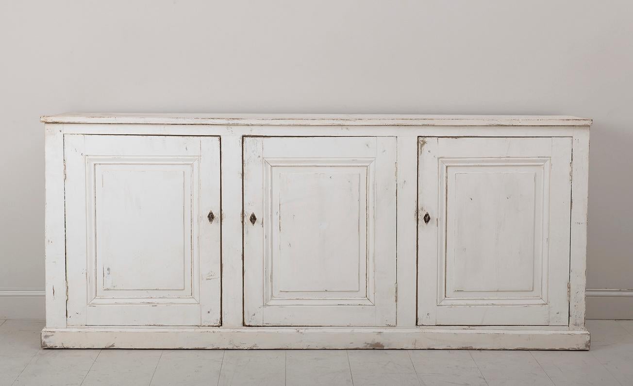 A 19th century French Louis Philippe enfilade found in Provence. This is a beautiful three-door sideboard or buffet in an aged ivory, time-worn patina, circa 1880. The lower left and right shelves are 27 inches W x 15.5 inches D.  The center shelf