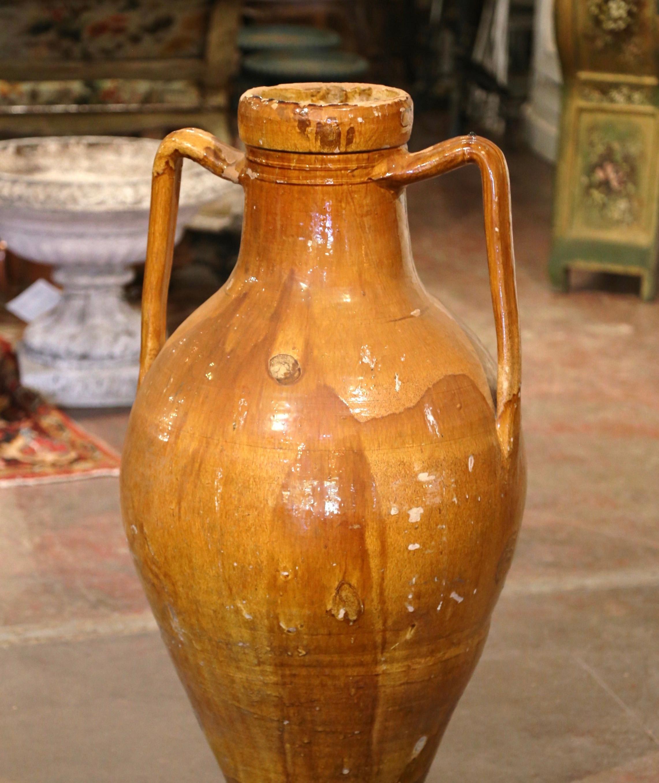 Add a Mediterranean touch to your indoor or outdoor spaces with this elegant antique terracotta Amphora. Crafted in Provence, southern France circa 1860, and built of earthenware, the large urn has a traditional round shape over a long neck; it is
