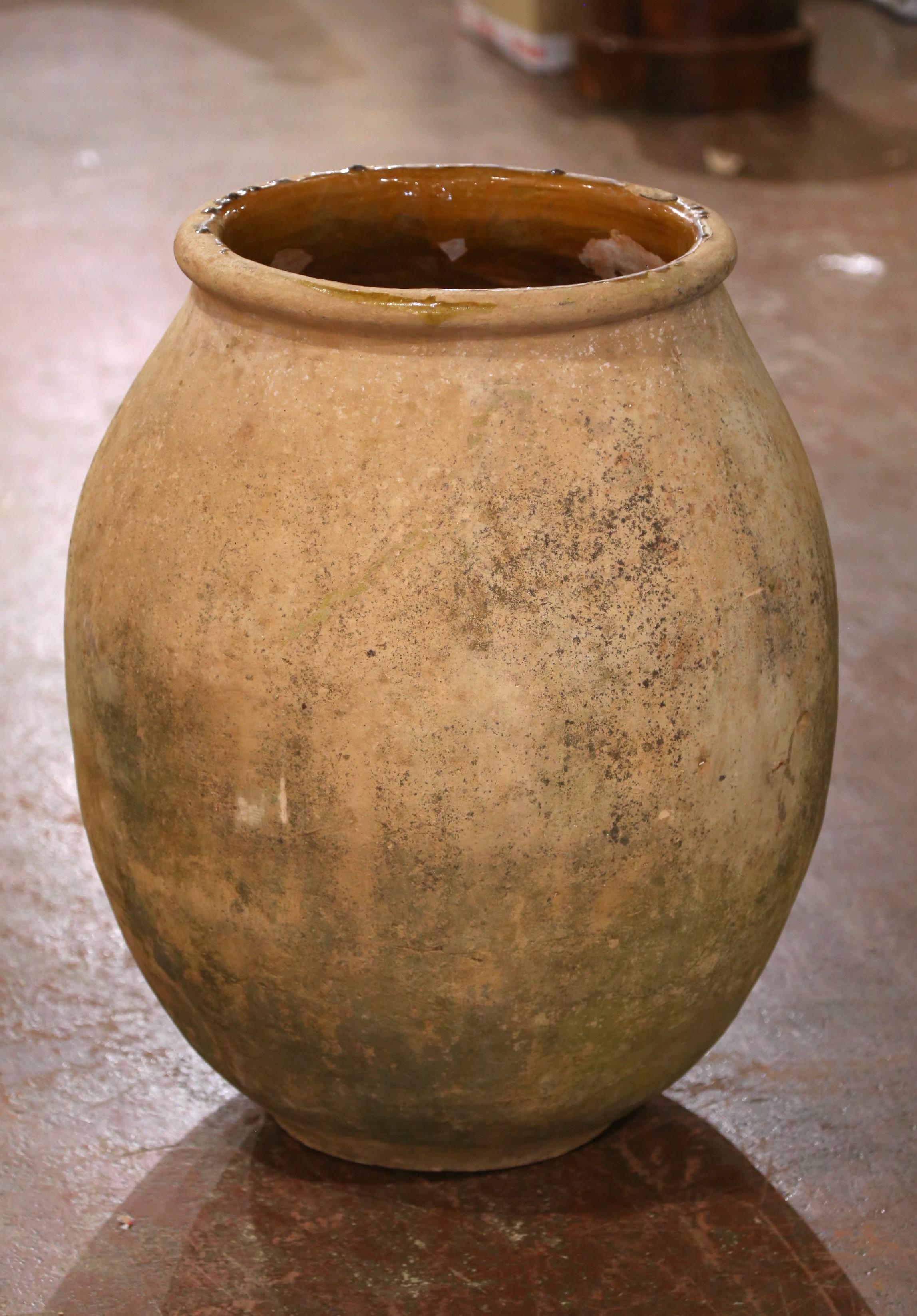 Esta gran tinaja antigua para aceite de oliva se fabricó en Biot, Provenza, hacia 1780. Hecha de arcilla rubia y modelada con la tradicional forma redondeada característica de la región, la vasija presenta un cuerpo ancho y bulboso y un cuello de