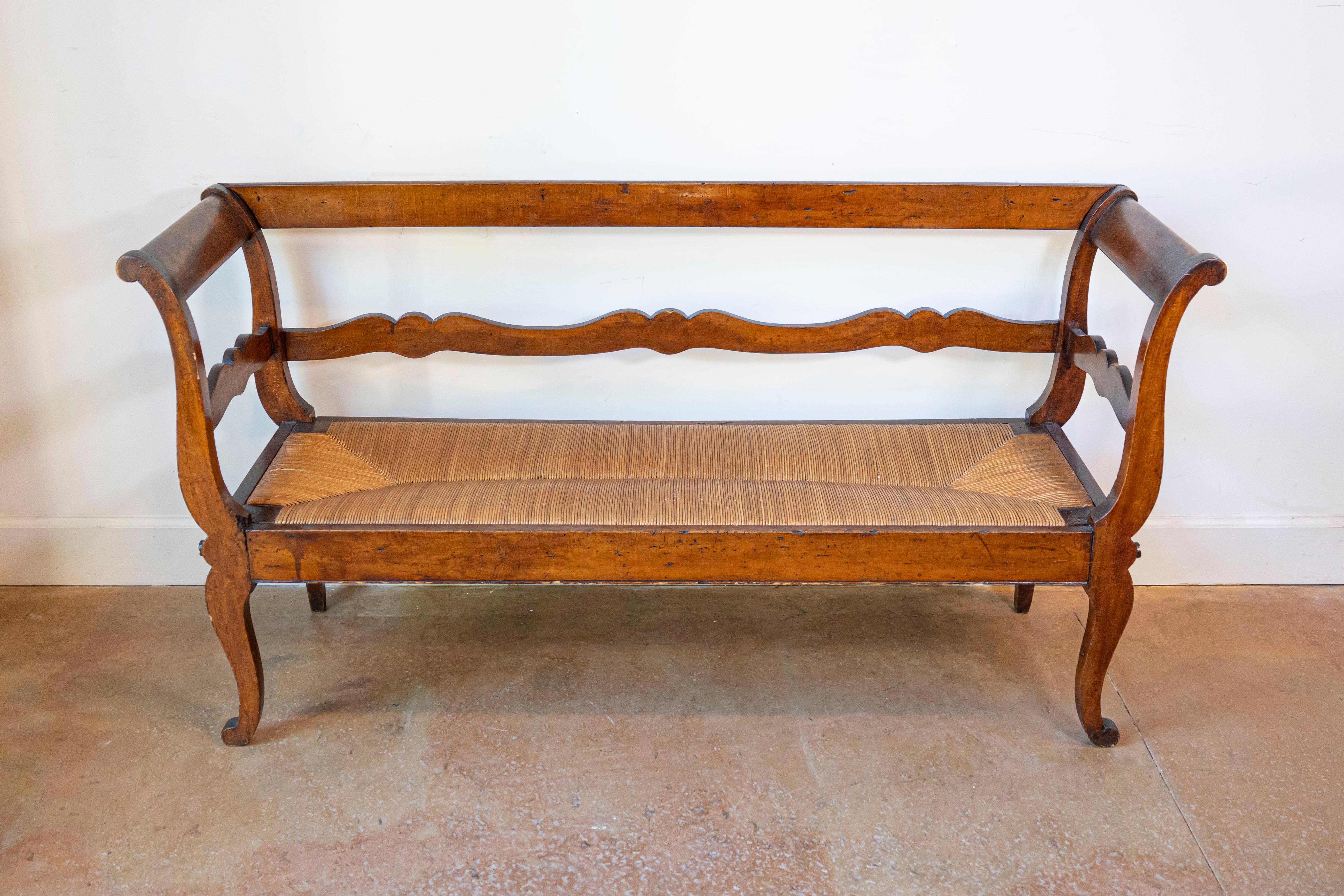 Questa incantevole panca da divano francese provenzale del XIX secolo è un esempio senza tempo di eleganza rustica e di fine artigianato. Realizzata in noce massiccio, la panca presenta uno schienale graziosamente curvo con un delicato design