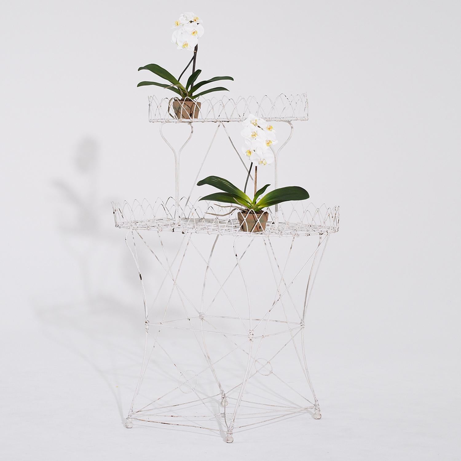 An antique oval French garden plant stand in white wire metal, in good condition. This oblong plant etagere is finely worked in metal and has a white washed antique patina. Ideal to hold the garden planters or ornamental florals for the interior