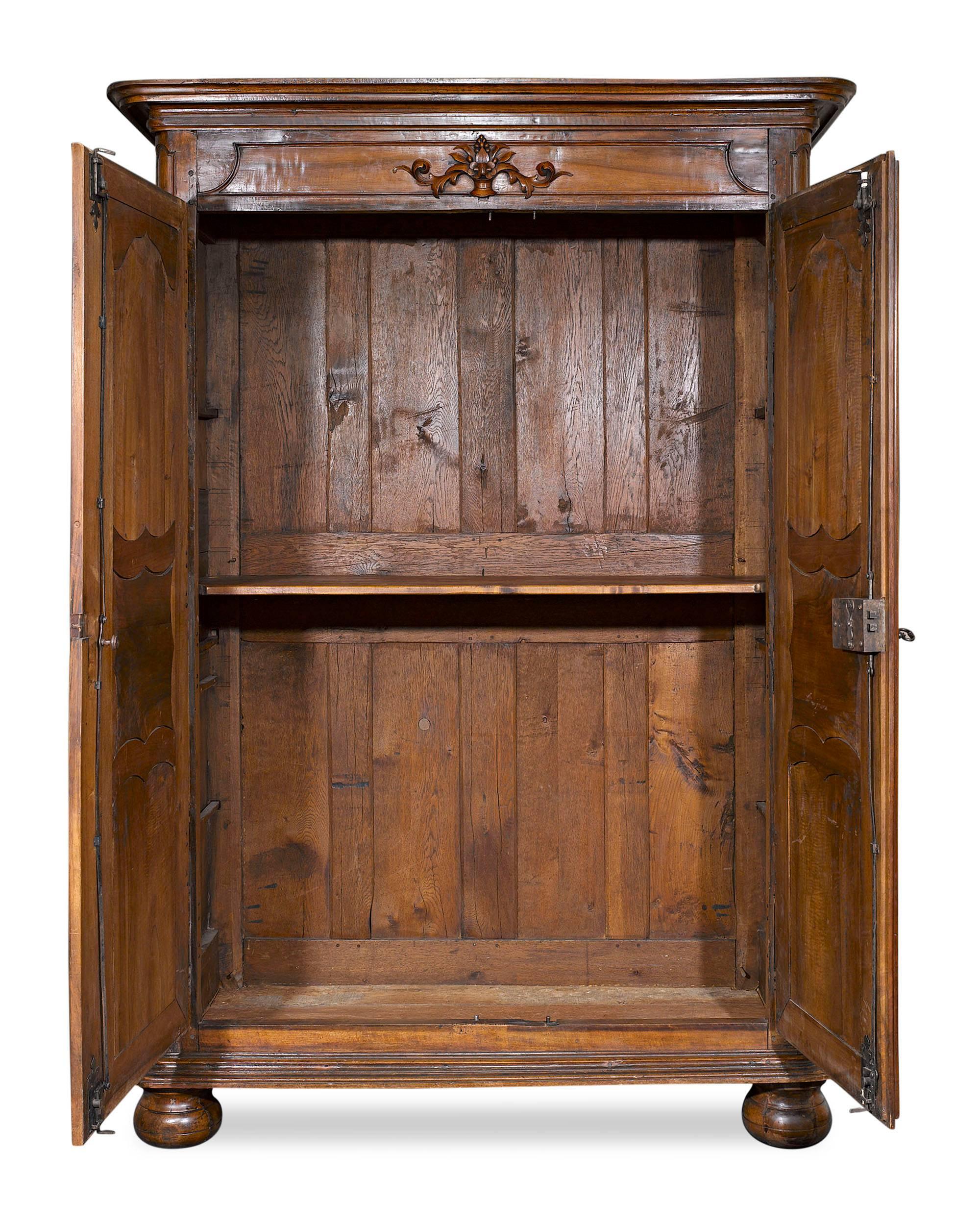 This fine French provincial double door armoire is beautifully crafted of fine walnut. Adorned with elegant, Rococo-inspired molding and featuring exceptional well-preserved, original hardware, this armoire provides ample storage space. The first