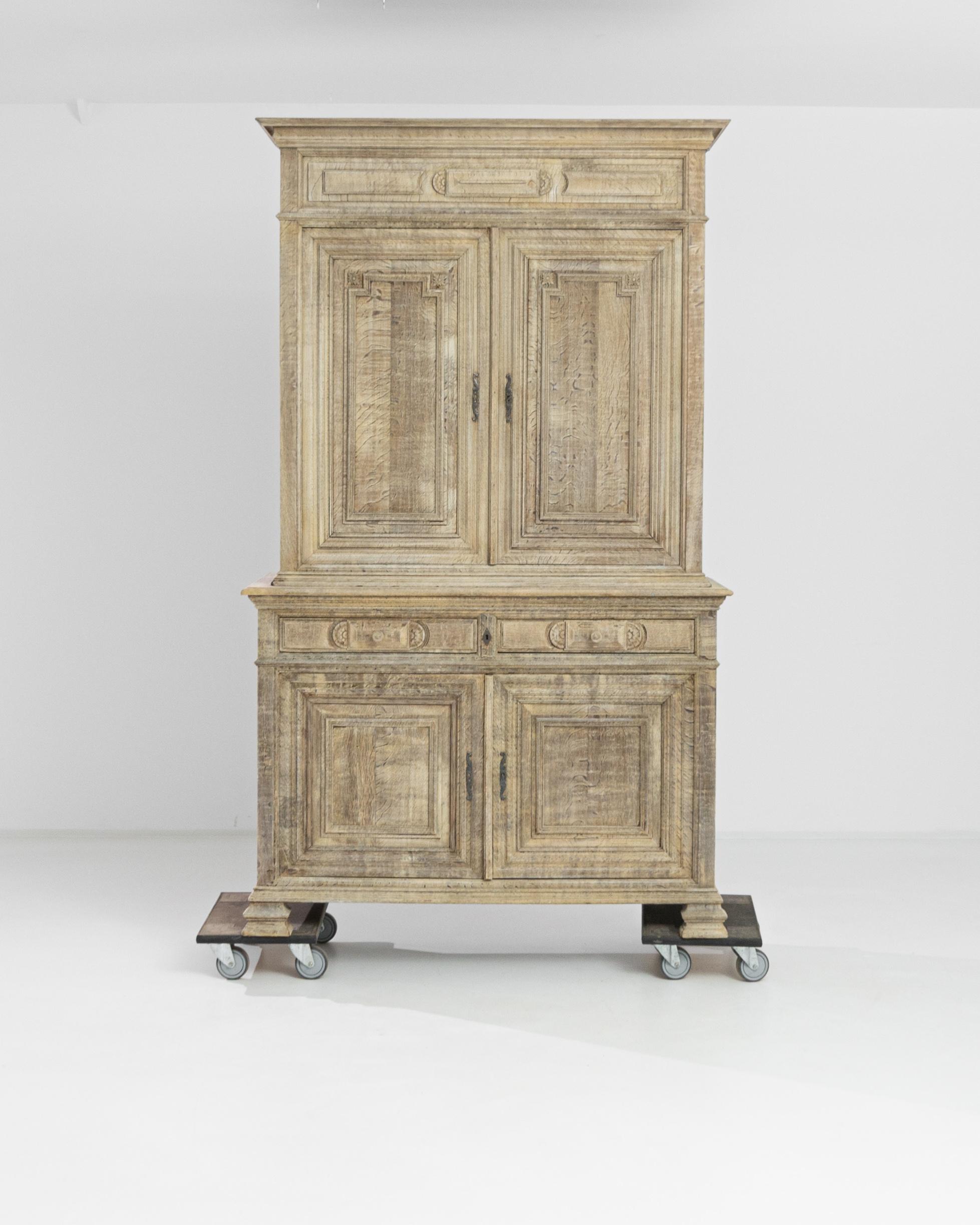 An antique cabinet from France, circa 1860, displaying a molded cornice, two front drawers, carved feet and an elegant carved case. The doors are ornamented with scrolled escutcheons, beveled lines and flower details, and open to reveal a powder