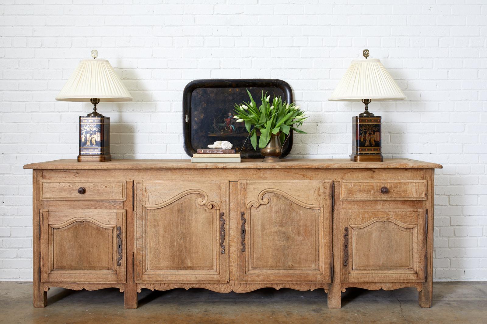 Rustic 19th century sideboard, enfilade, or buffet made in the French Provincial style. Features a bleached oak finish with a beautifully aged patina on the oak which showcases the lovely wood grain. Period correct brass hardware and lock plates