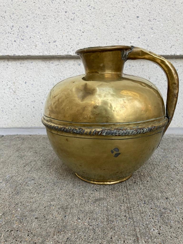 A well used circa 1850 century brass milk jug from Brittany, France. Wonderful hand made craftsmanship, with dents and dings from use. With scalloped collar and raised rope decoration across the midsection. Simple beauty for a very practical item.
