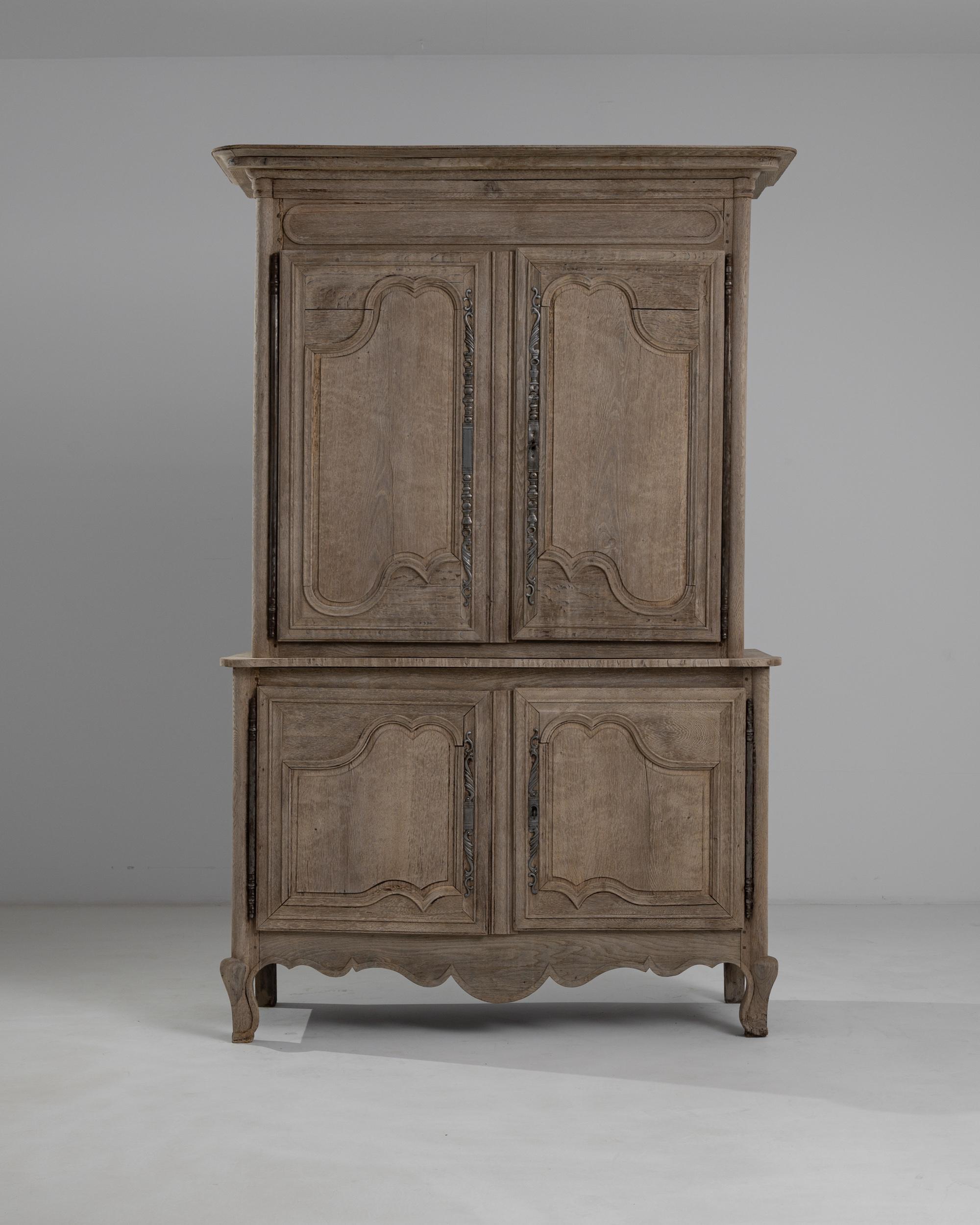 La tonalità cenerina del rovere sbiancato accentua la grandezza di questo buffet d'epoca 'a deux corps' realizzato a mano in Francia intorno al 1850. Coronata da un cornicione modanato, questa cassapanca vanta profondi intagli curvilinei delle ante