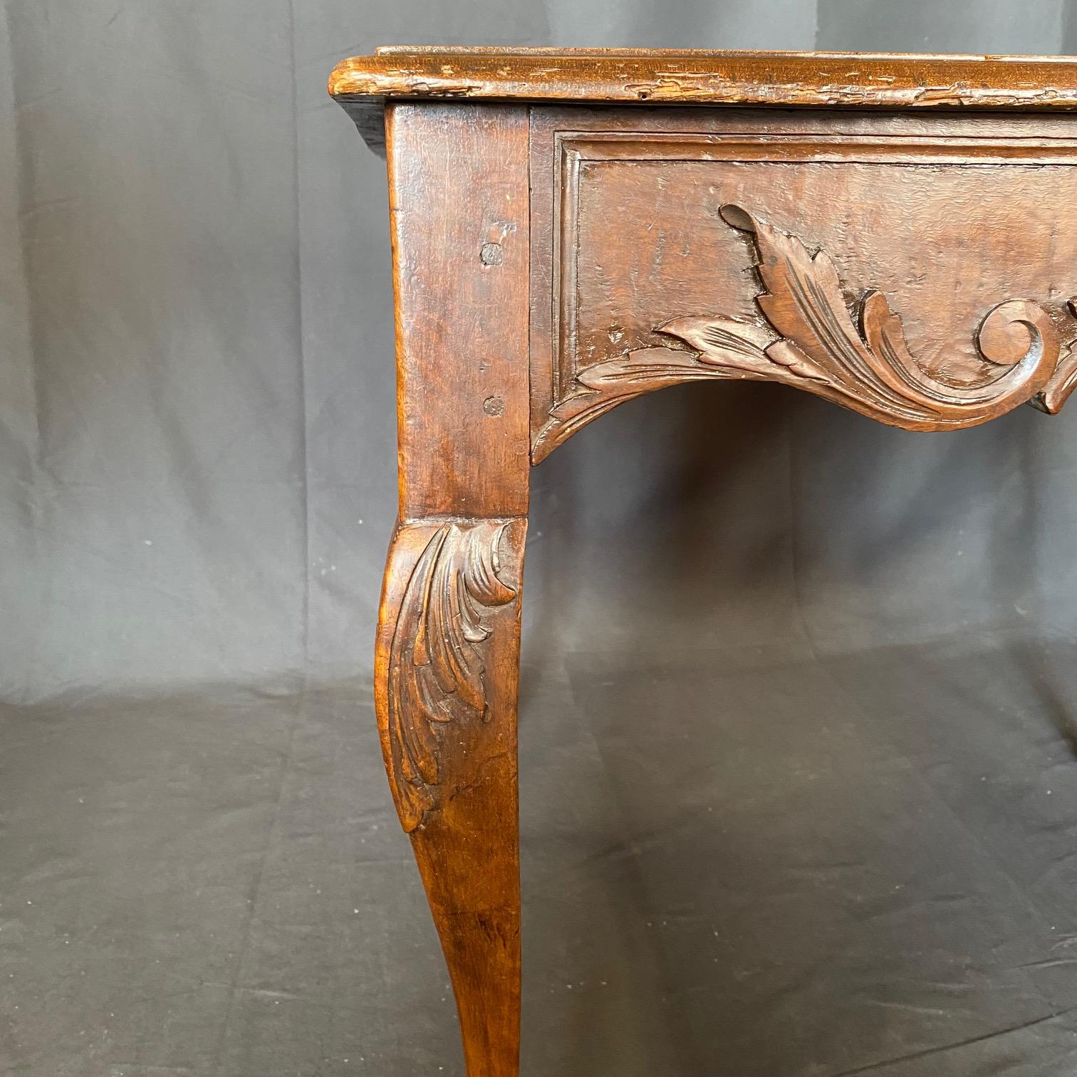 Achetée dans le sud de la France, cette table d'appoint Louis XV en noyer du XIXe siècle est magnifiquement travaillée à la main ! Les sculptures détaillées des feuilles d'acanthe et des pièces centrales du tablier floral sont complétées par les