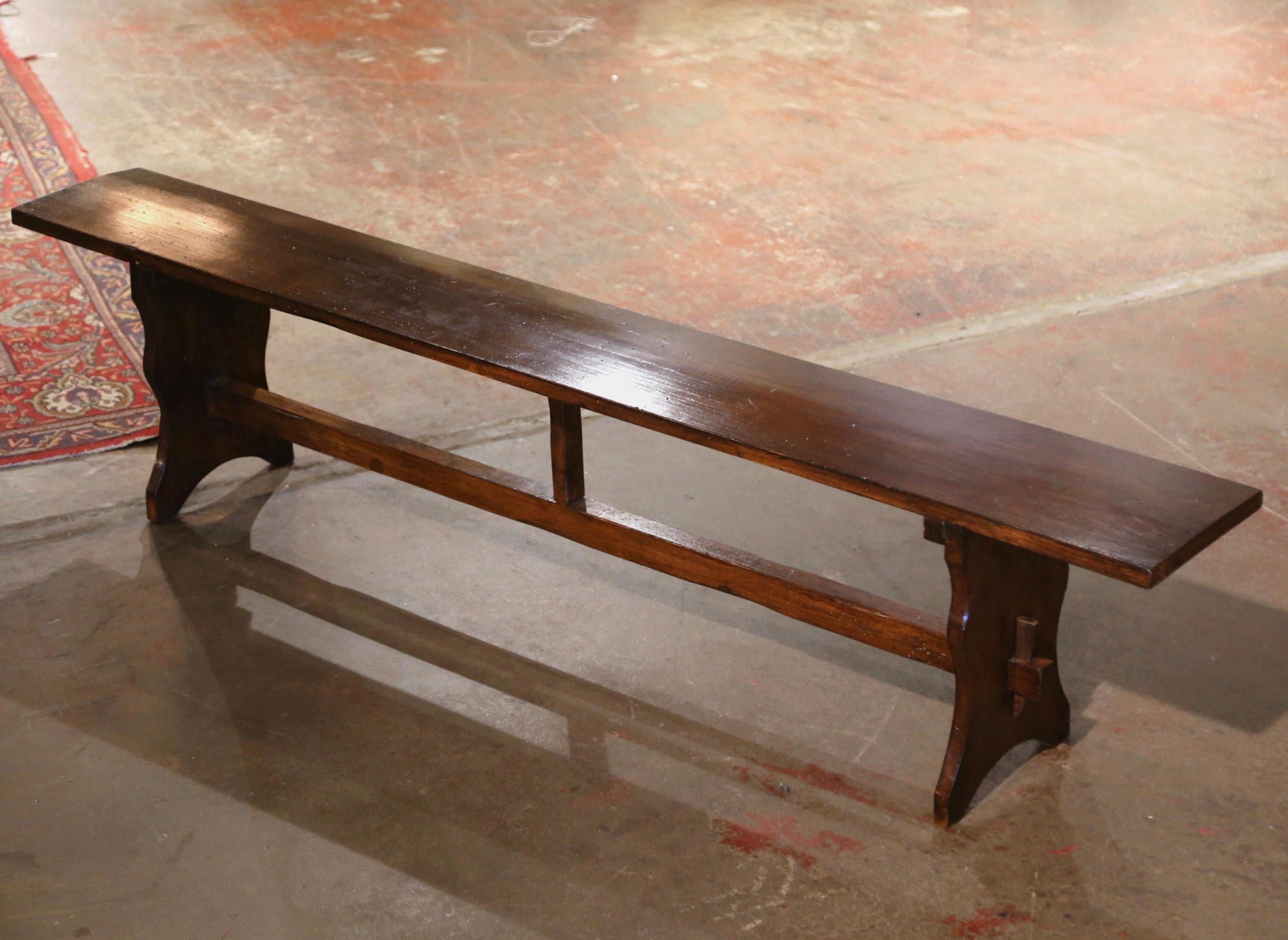 Dressed a farm table with this elegant antique provincial bench. Crafted in the Poitou region of France, circa 1890, and carved of walnut wood, the farmhouse bench stands on boot-jack legs and joined by a central stretcher. The seat is built with