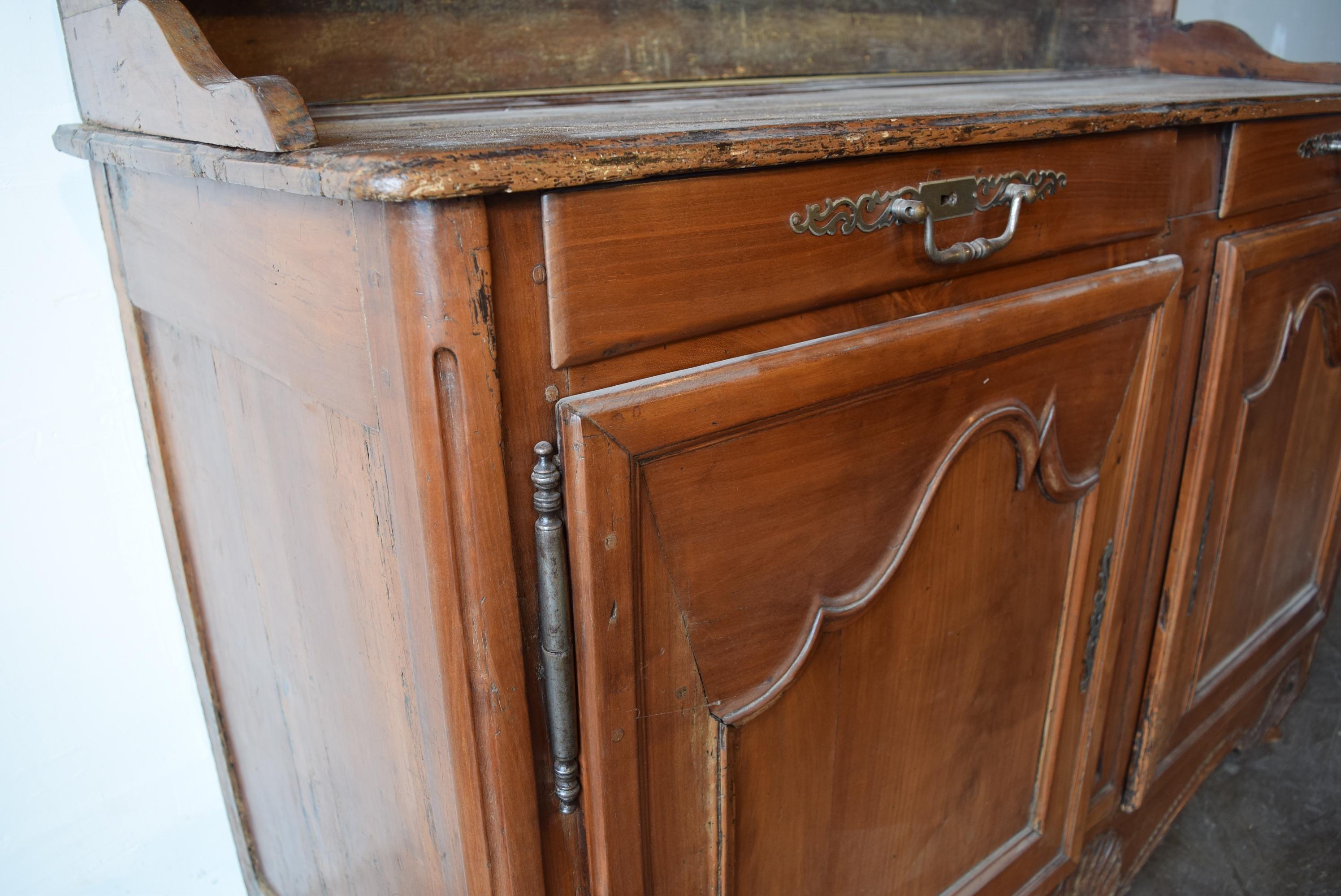 French cherrywood kitchen cupboard/vasselier, c. 1860-1880. Handsomely carved with double drawers above cabinet doors featuring iron fiche hinges. Both drawers feature original iron pulls and matching iron escutcheons on each door. The scallop shell