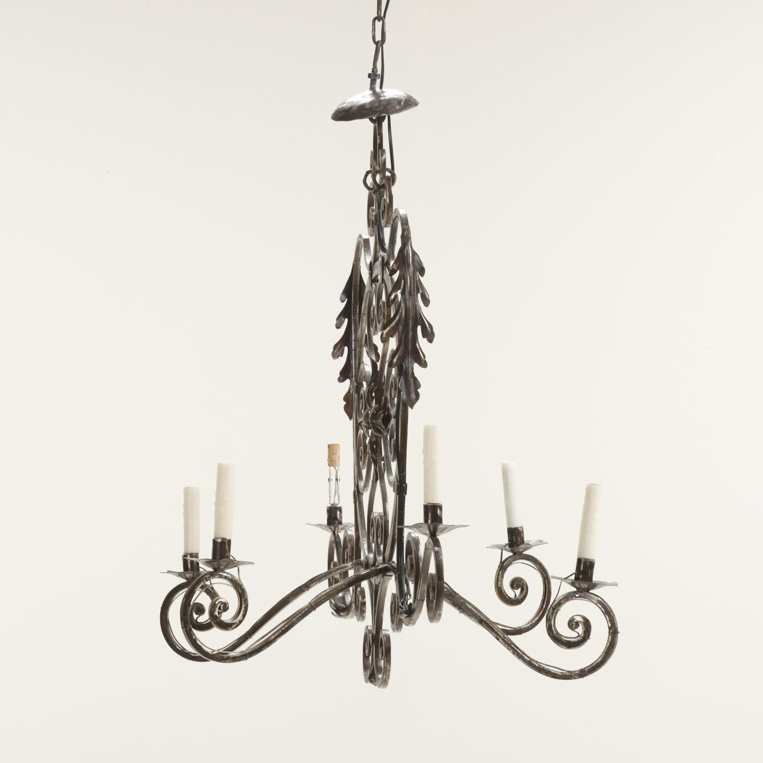 Un sorprendente lampadario provinciale francese del XIX secolo, forgiato a mano in acciaio decorativo con una patina splendidamente invecchiata. Realizzato nel sud della Francia intorno al 1880, questo apparecchio scultoreo è caratterizzato da sei