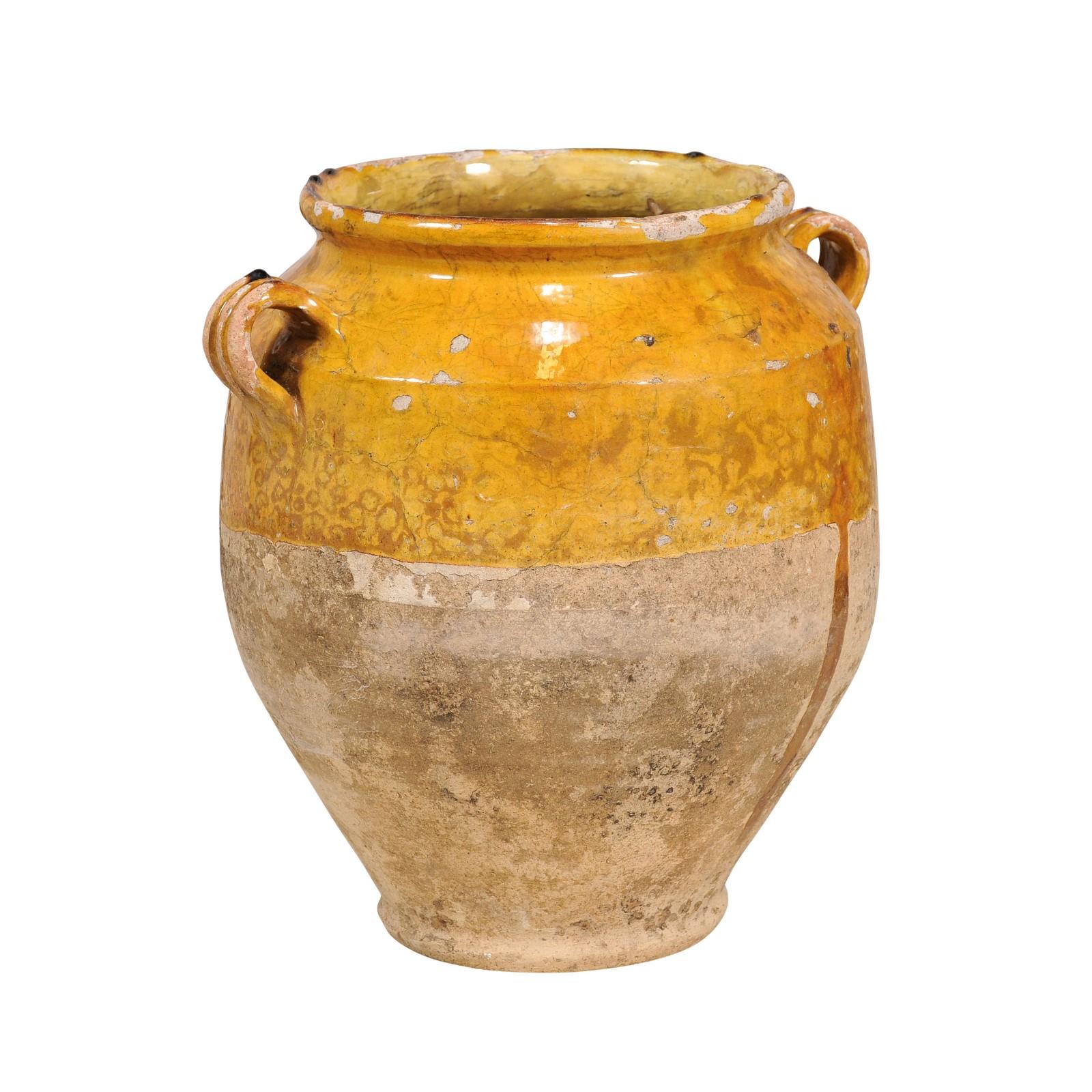 A French Provincial pot à confit pottery from the 19th century with yellow glaze, two lateral handles and rustic patina. This 19th-century French Provincial pot à confit is a delightful relic of rustic culinary history. The pot, traditionally used