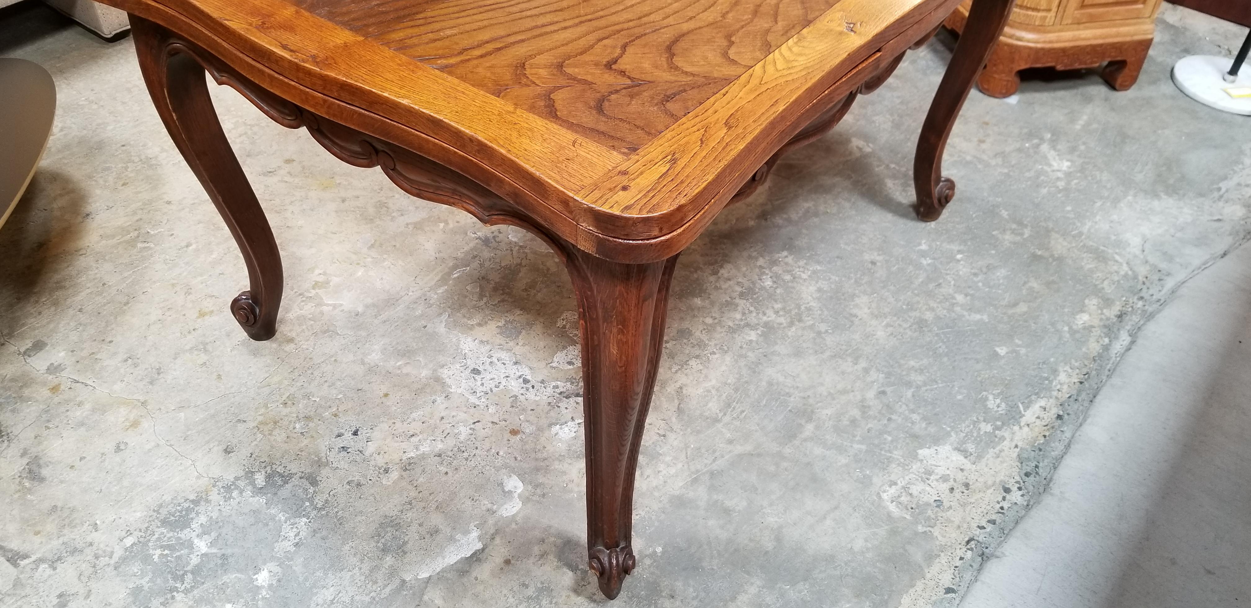 A Country French or French Provincial style expanding draw-leaf dining table with carved apron and carved cabriole legs. Parquetry top with matching design on table leaves. Deep, rich patina to original  finish with age appropriate wear.