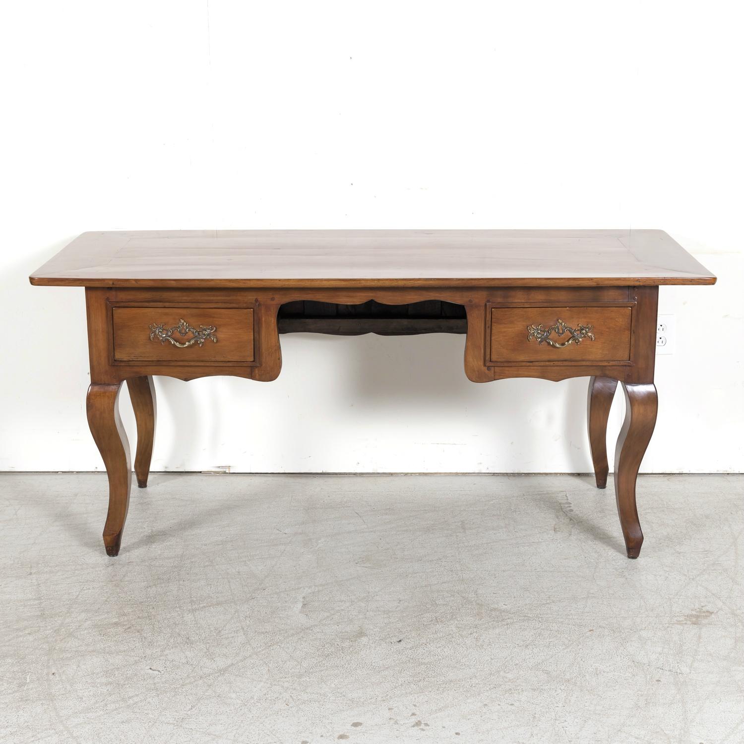 A 19th century French Provincial Louis XV style bureau plat or writing desk handcrafted of solid cherry wood in Dinan, a beautiful medieval-walled town in the Brittany region, circa 1880s. This handsome desk has an inset rectangular plank top over a