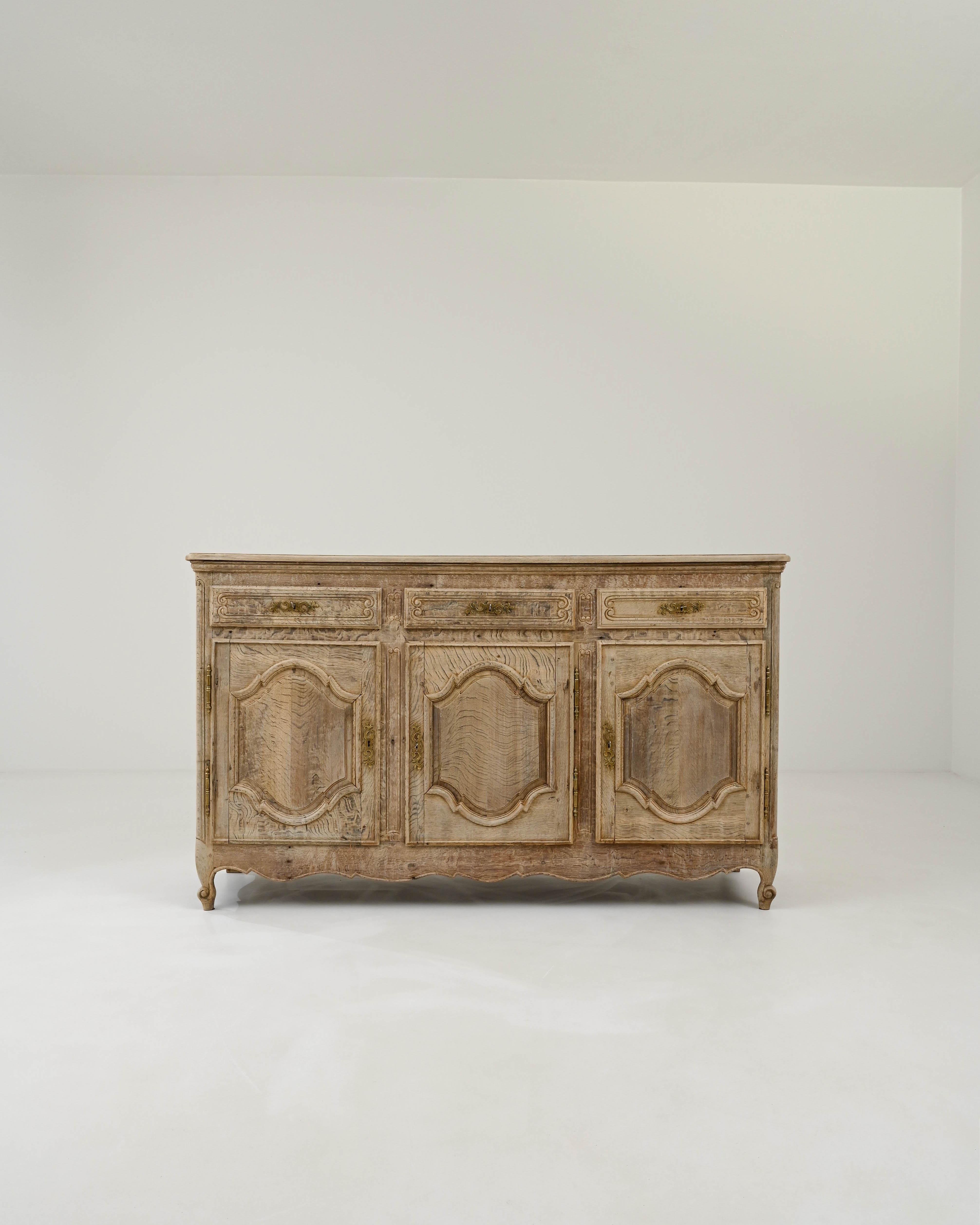 With its charming provincial design and warm natural finish, this antique oak buffet is a covetable find. Hand-crafted in France in the 1800, the doors of the three spacious cupboards are decorated with elegant carved paneling; tightly coiled