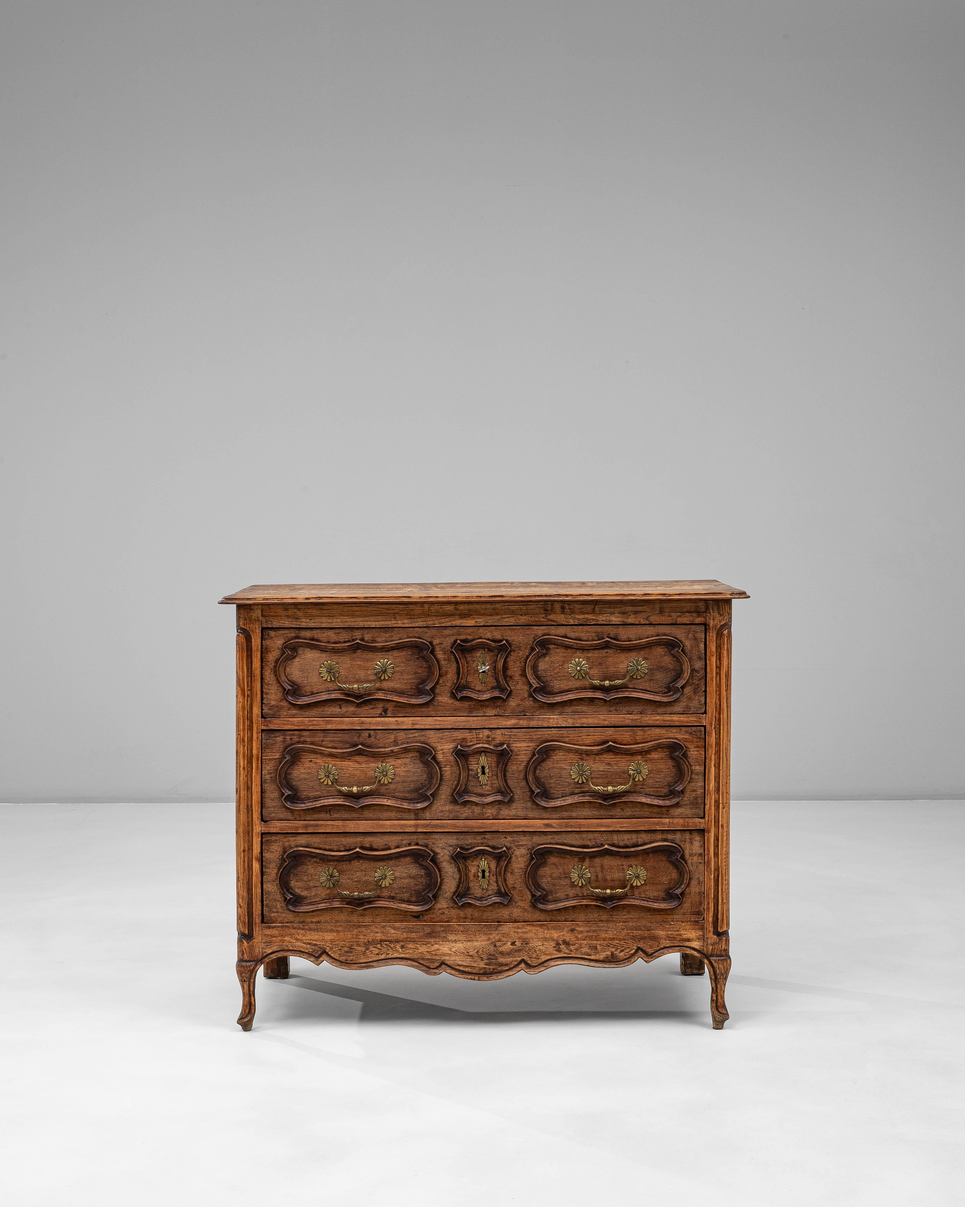 Questa cassettiera in rovere della provincia francese del XIX secolo mostra le curve aggraziate e gli ornamenti raffinati caratteristici dell'artigianato provinciale. I tre cassetti sono caratterizzati da frontali splendidamente sagomati con bordi