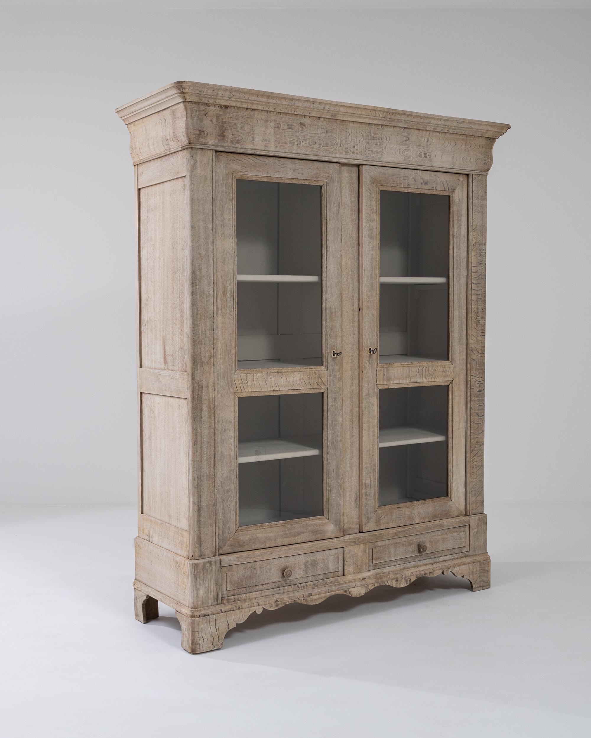Simple yet elegant, this oak vitrine makes a delightful Provincial accent. Made in France in the 1800s, the silhouette is clean and restrained; the elegant contour of the apron brings out the attractive symmetry of the design. The windows of the