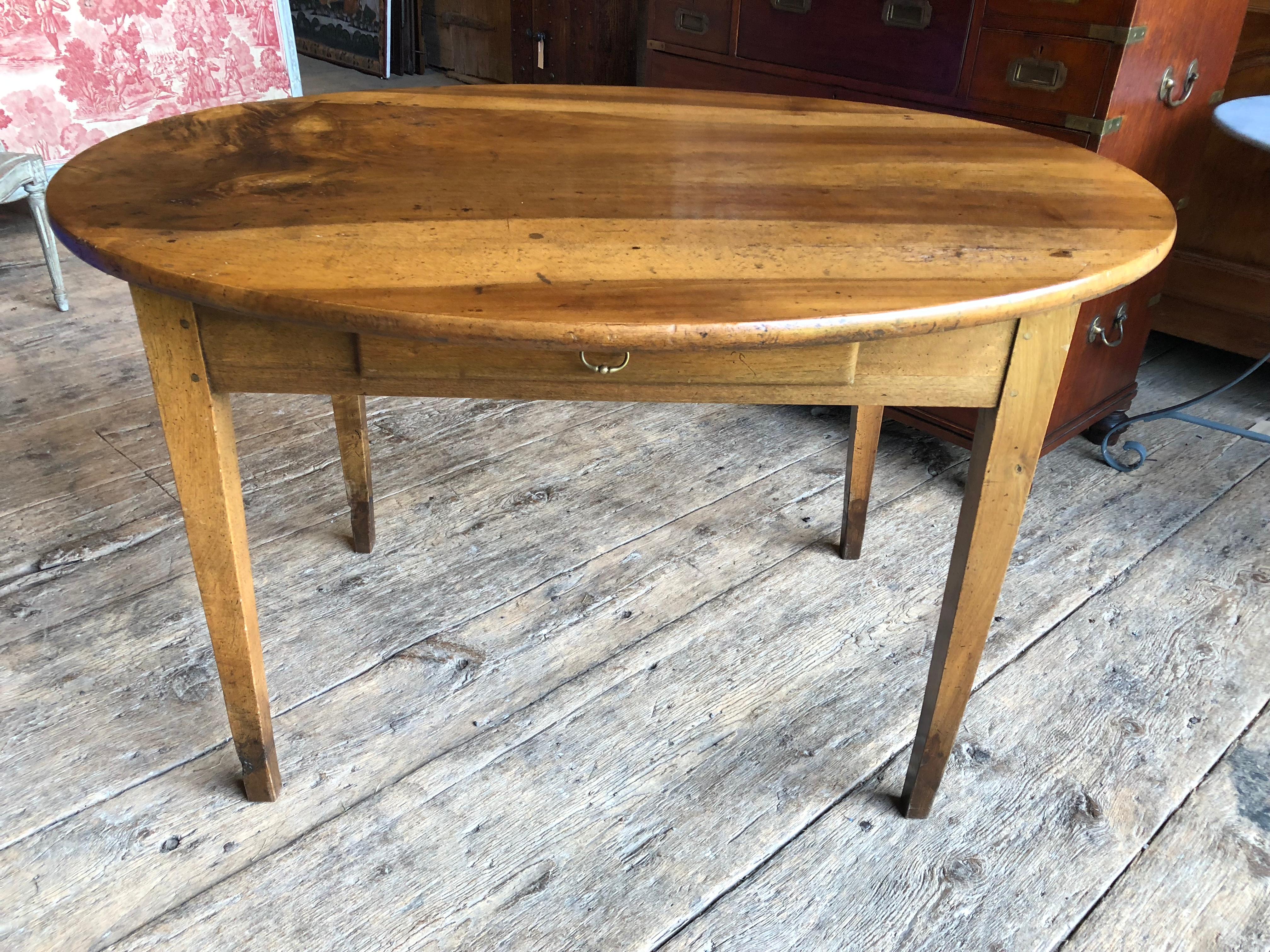 An oval breakfast table or writing table in walnut with one drawer and simple tapered legs from France, circa 1850. Nice patina and great size for an apartment or guest room.