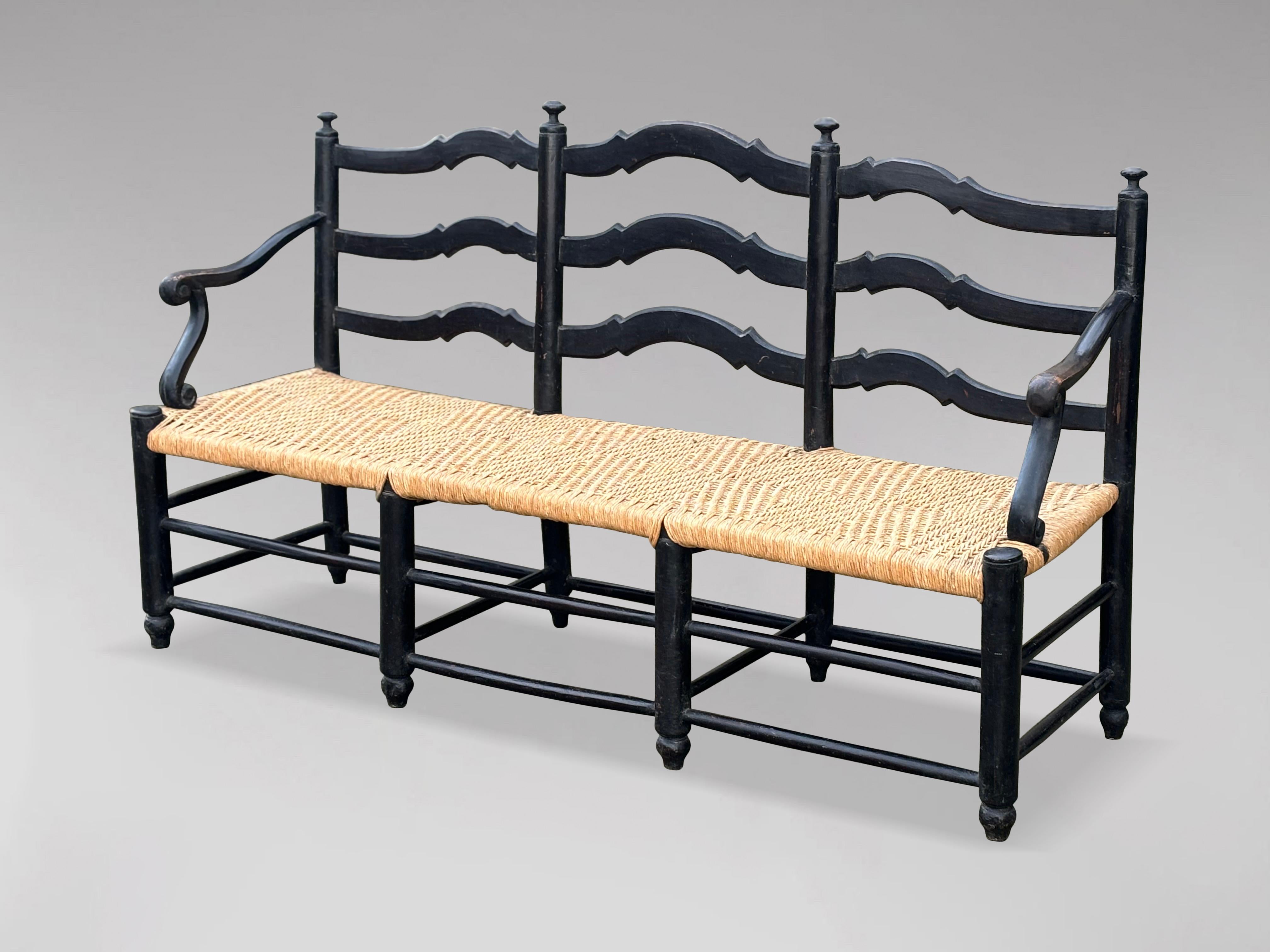 A very decorative late 19th-century French Provincial painted bench with a handwoven rope seat, combining the charm and elegance of French country style with the warmth of natural materials for a timeless, rustic aesthetic. This three-seater bench