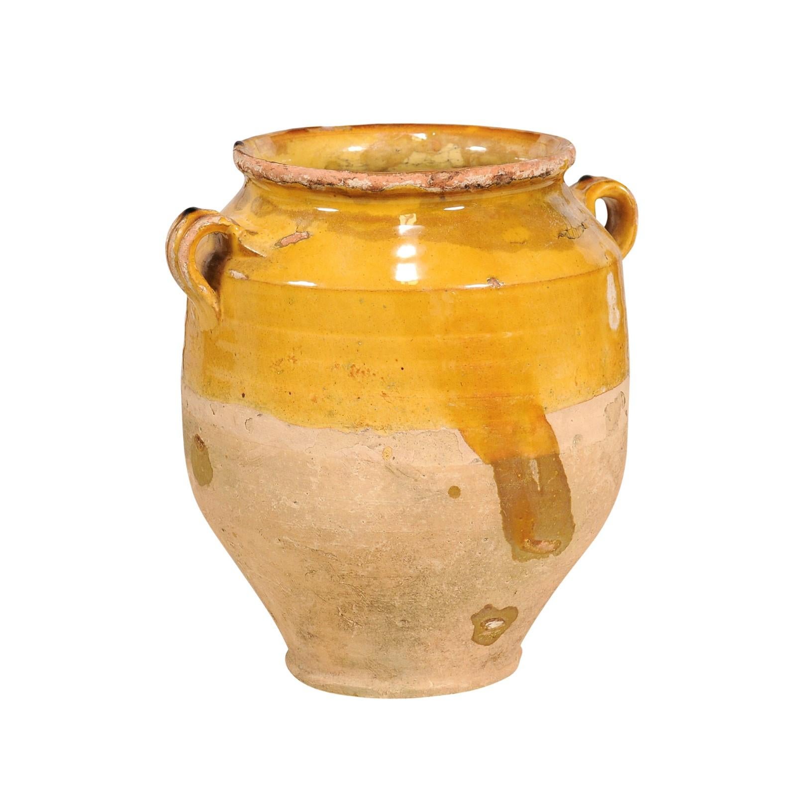 A rustic French Provincial pot à confit from the 19th century with yellow glaze and double handles. Embrace the essence of rustic French charm with this exquisite 19th-century French Provincial pot à confit, a piece steeped in history and character.