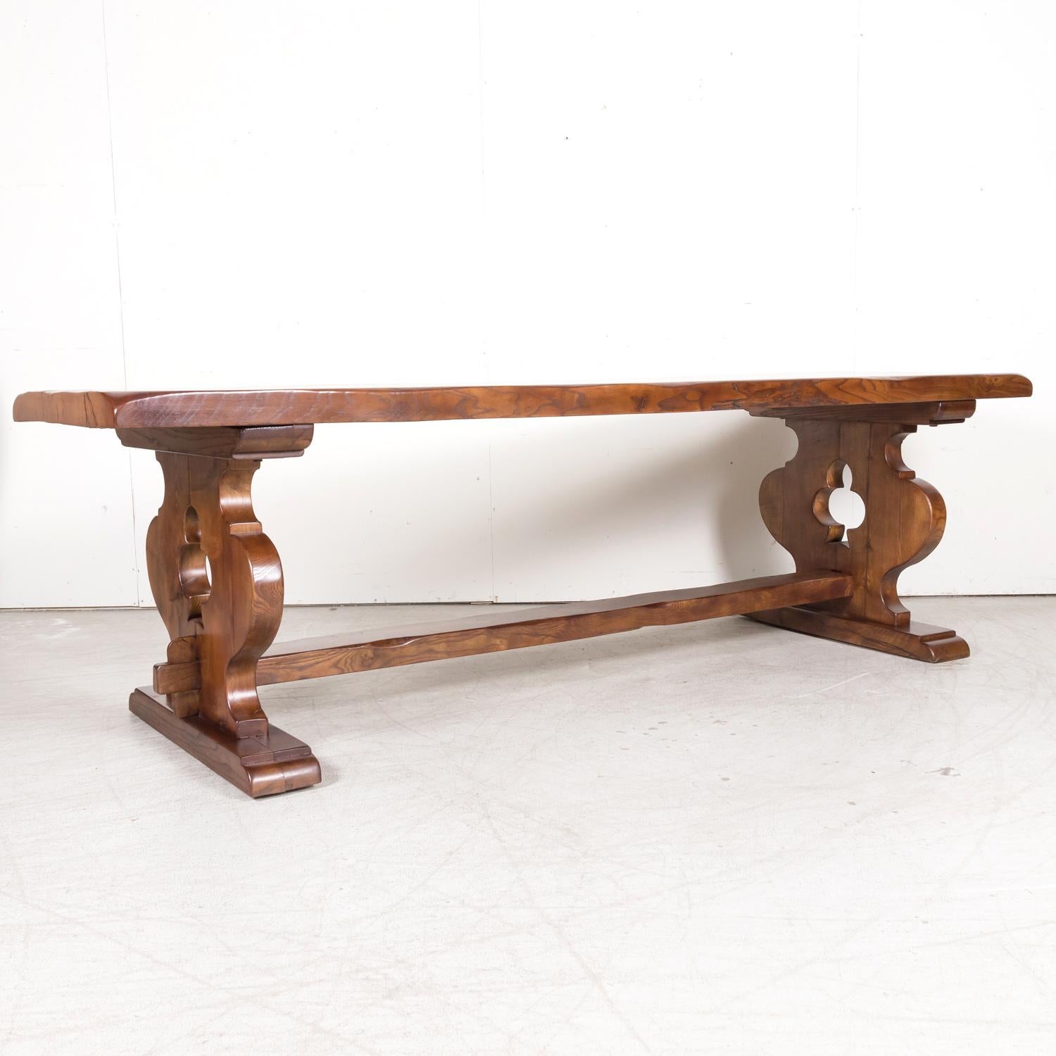 A 19th century French provincial trestle table handcrafted of solid chestnut by talented artisans in the Normandy region of France, circa 1890s. This beautiful French dining table has a rectangular plank top supported by carved trestle bases that