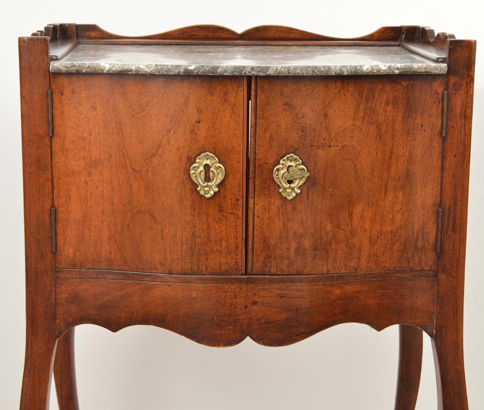 This charming French provincial marble top commode features a carved top edge enclosing the marble top, two doors, a shaped apron and four finely shaped cabriole legs. Both sides have shaped cut outs for lifting.