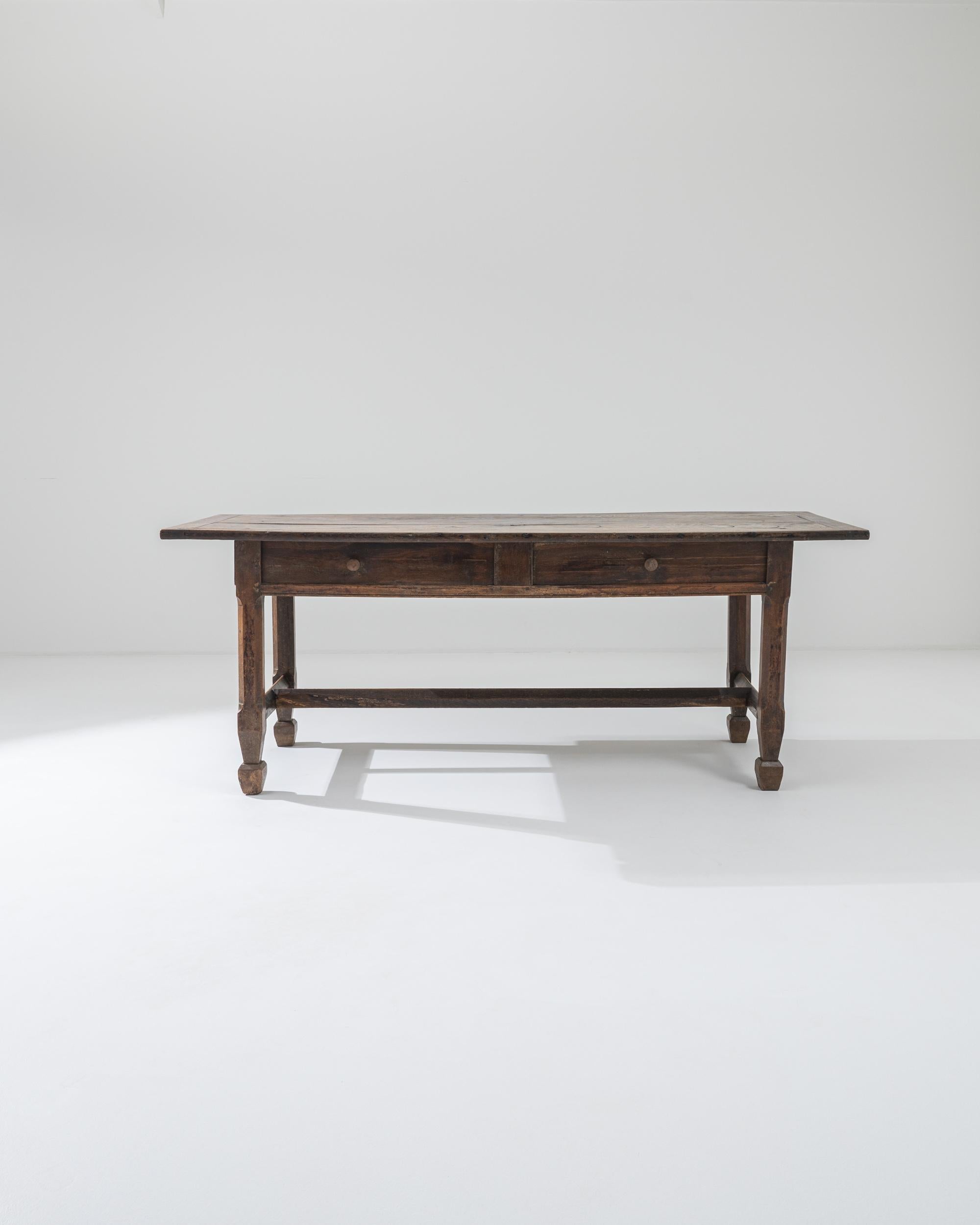 This antique wooden table combines a Provincial silhouette with an attractive original patina. Made in France in the 1800s, the simple rectilinear shape is enlivened by subtle details—the gentle contour of the stretcher blocks; the rugged taper of