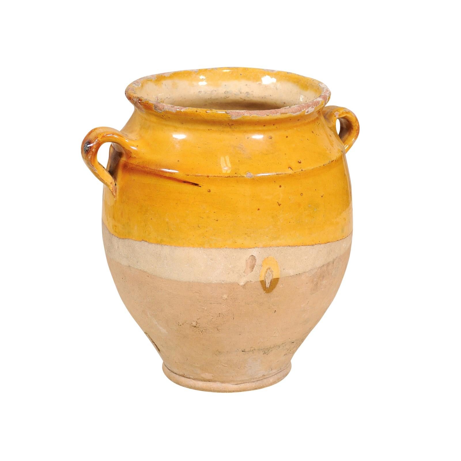 A French Provincial pottery pot à confit from the 19th century with yellow glaze, double handles and rustic character. This French Provincial pot à confit, hailing from the 19th century, is a splendid example of traditional pottery with its vibrant