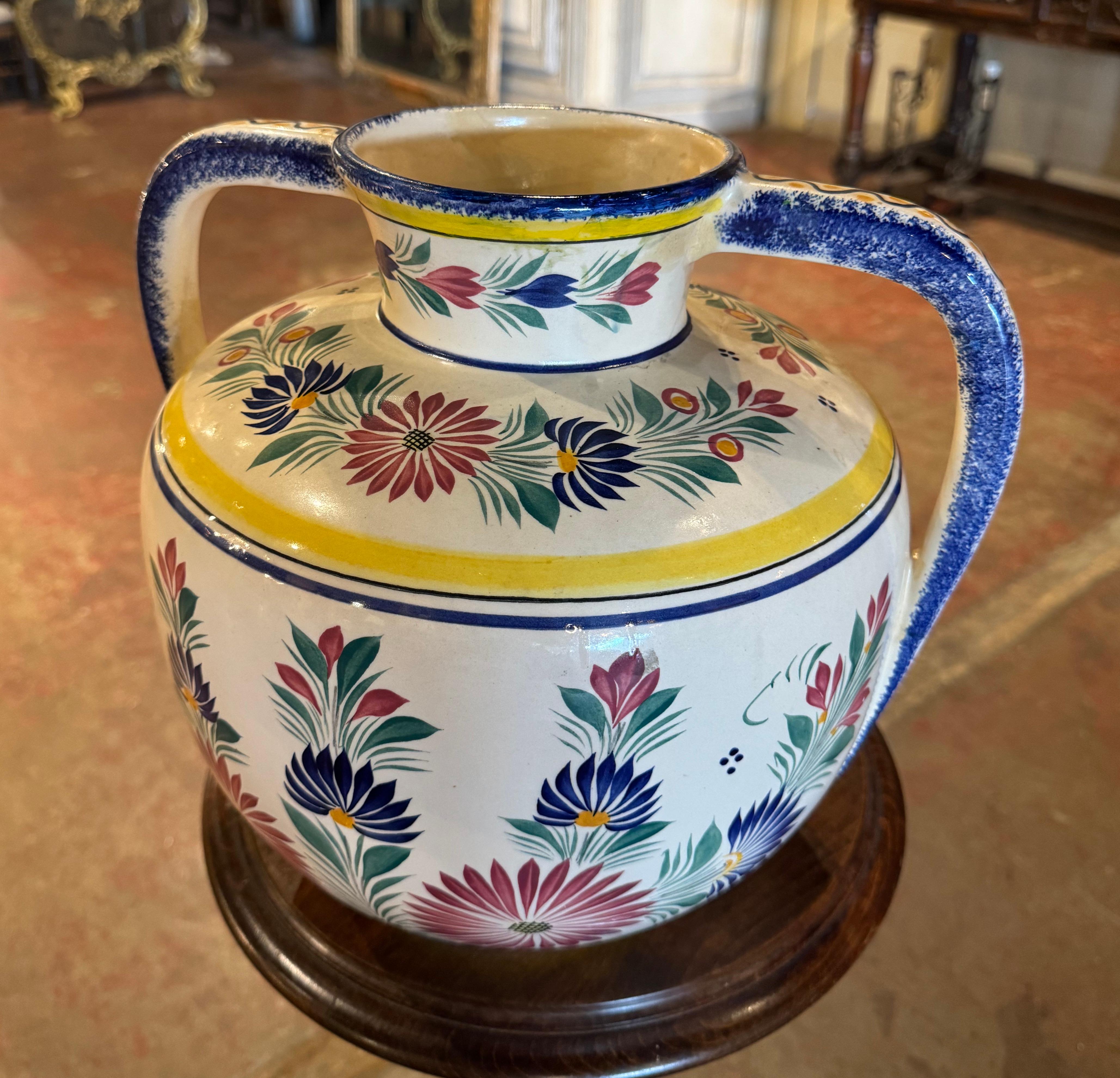 Completa tu colección de loza con este colorido jarrón antiguo de Bretaña. Fabricado en Quimper, Francia, hacia 1880, el jarrón tiene forma redonda y está provisto de dos asas laterales. El recipiente presenta motivos florales pintados a mano por