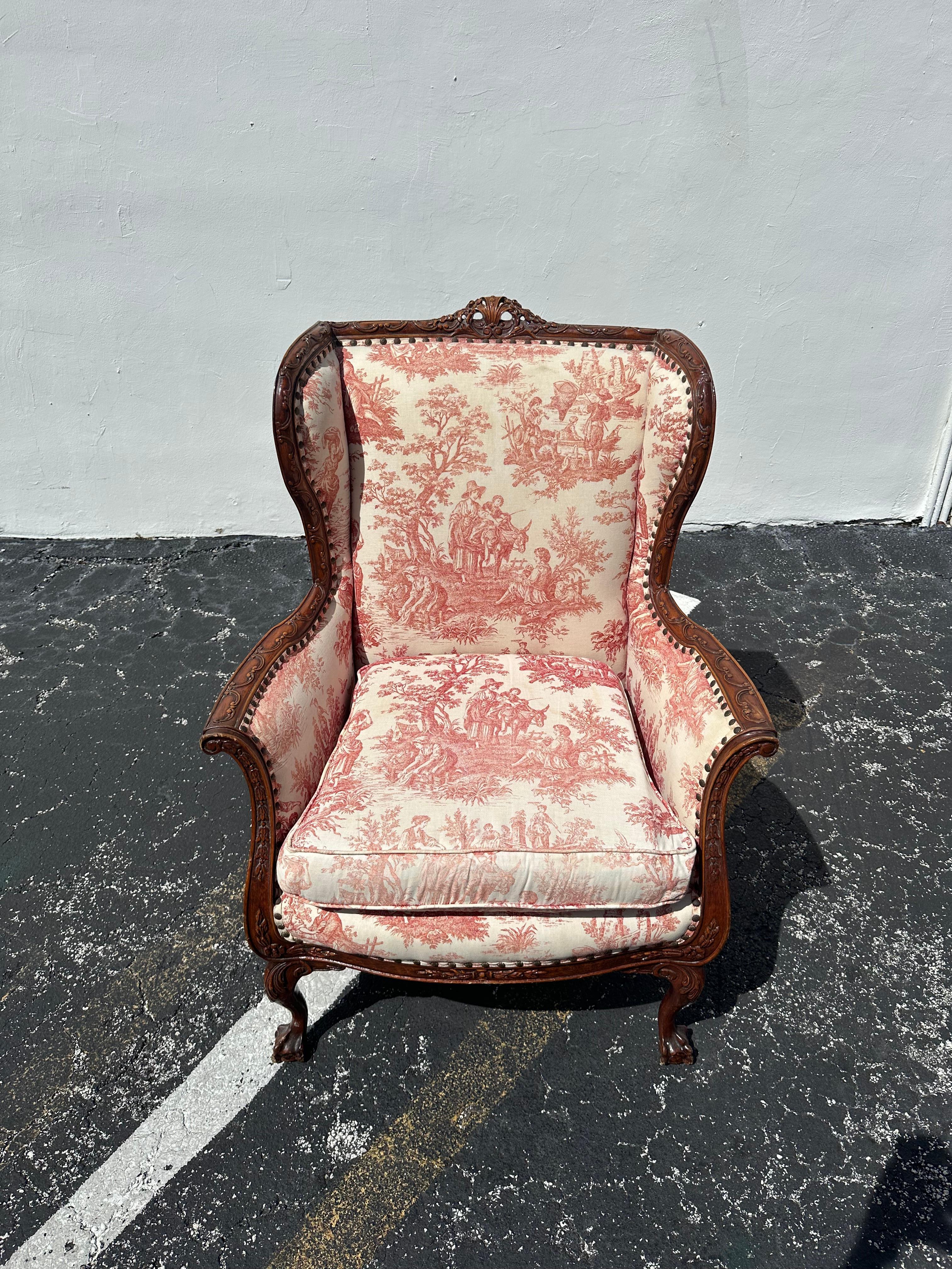 Transport yourself back to the sleek and sophisticated 19th Century with this exquisite original French toile ornate wood wingback chair. The ultra rare chair exudes an air of history and refinement. Outstanding design is exhibited throughout. The