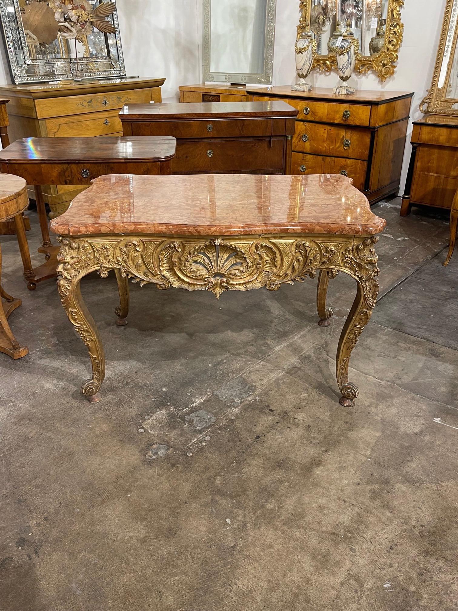 Very fine 19th century French Regence style carved and giltwood center table. Beautiful intricate carvings and lovely rose colored marble top. An exceptional piece!