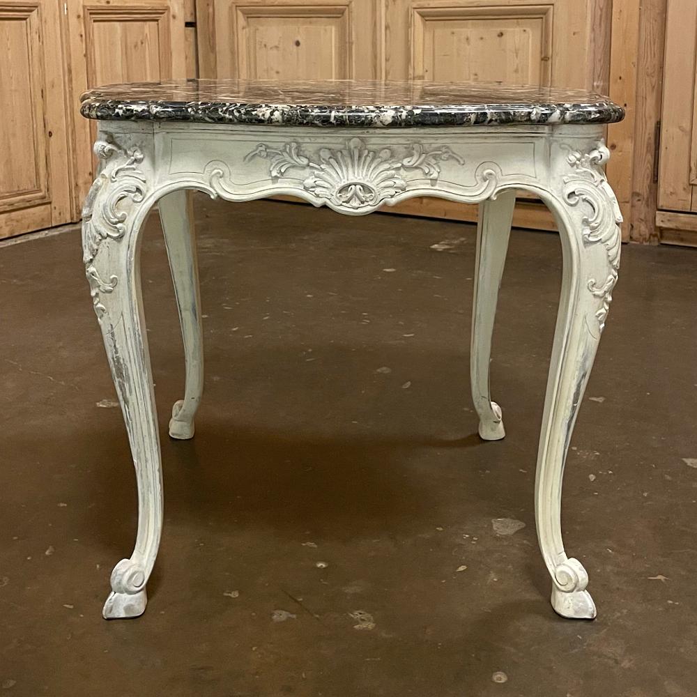 Just the right size for your favorite seating group, this 19th century French Regence Painted marble top table was sculpted in the Regence style and fitted with contoured and beveled marble, the beautifully patinaed hand-applied painted finish is