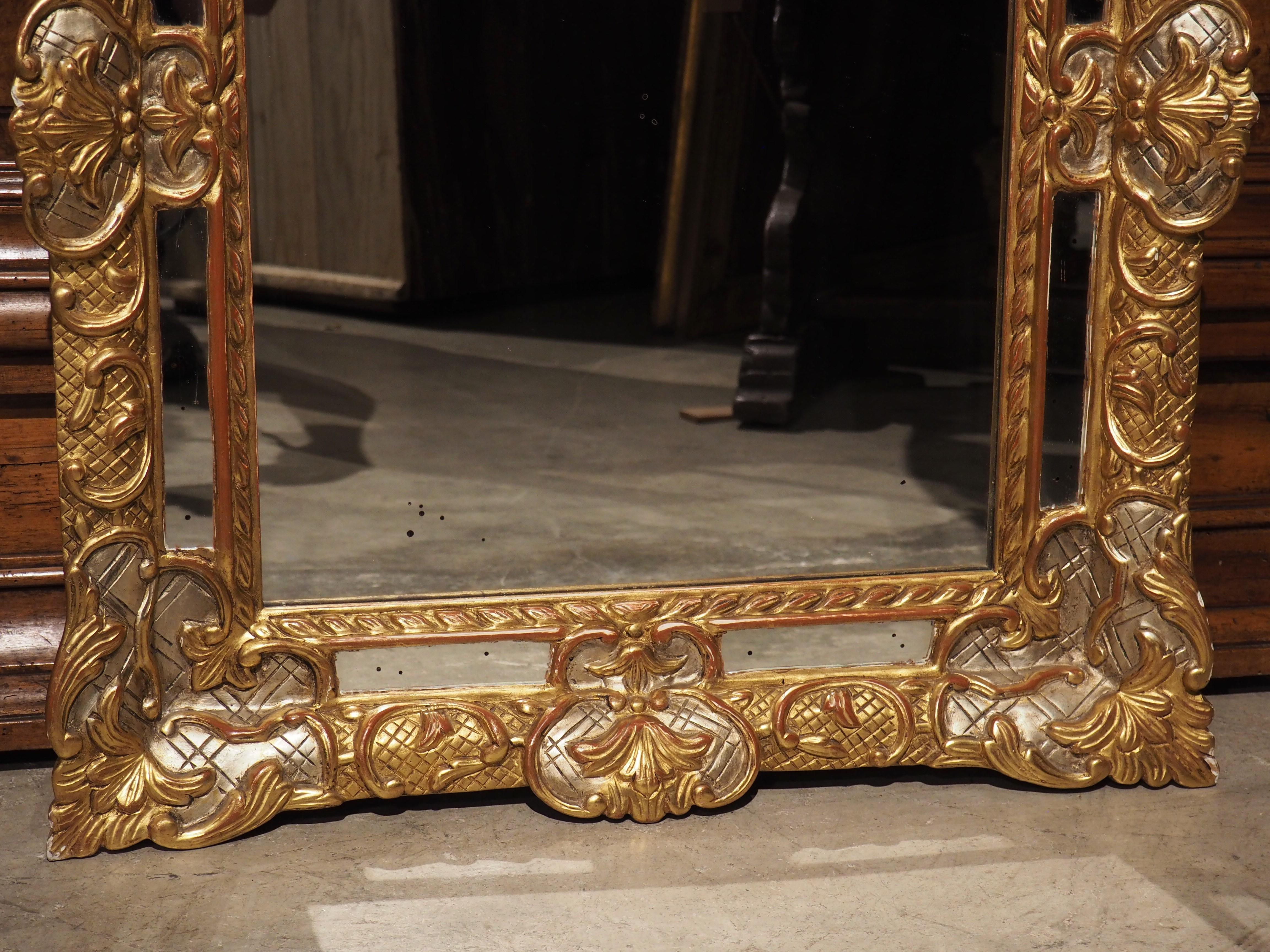 This stunning silver and gold gilt wall mirror has eight side mirrored panels separated and held in place from the main center mirror by giltwood ornamentation. The arrangement of the separate pieces of glass seen here gives this type of mirror its