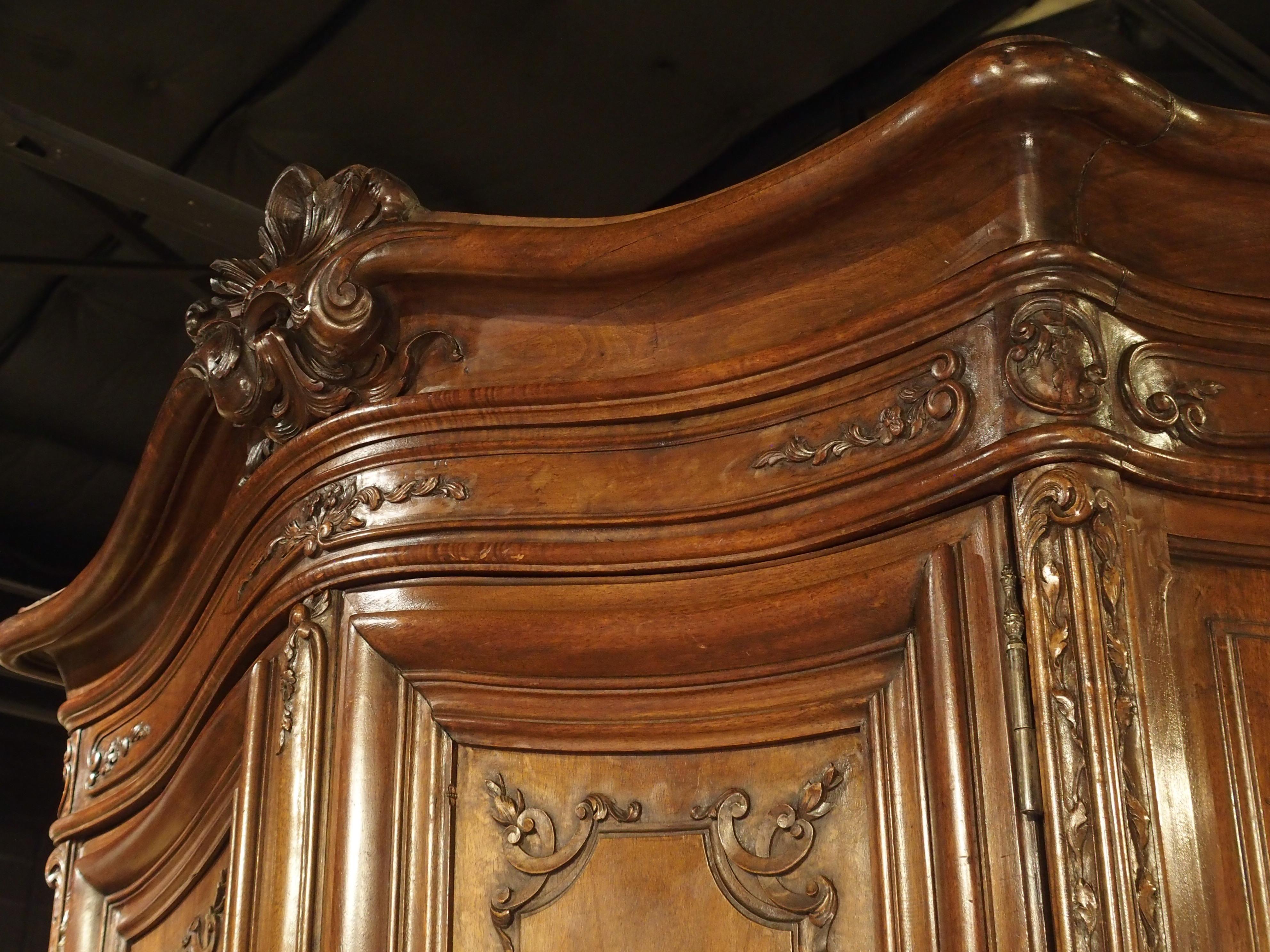This impressive walnut buffet deux corps was produced in France during the 1800’s. The two-body buffet was hand-carved with bombe (convex) faces and is in the style of Regence. The Regence period occurred after the reign of Louis XIV, when France