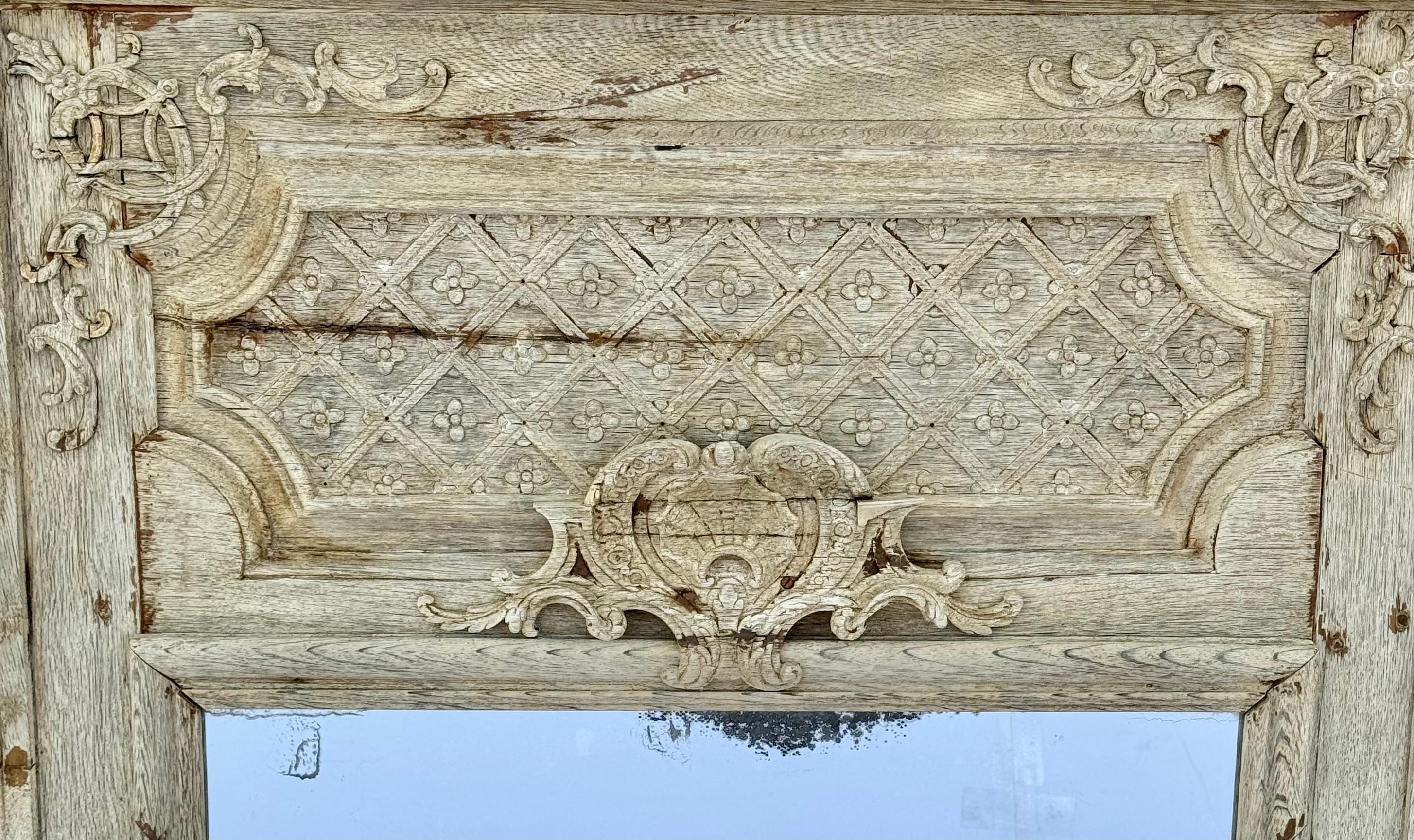 19th Century French regency style Trumeau mirror. Hand-carved with intricate scrolling and medallions on top and sides. This rare piece has a wonderfully bleached finish to give it a perfect patina and revealing stunning wood grain patterns. A grand