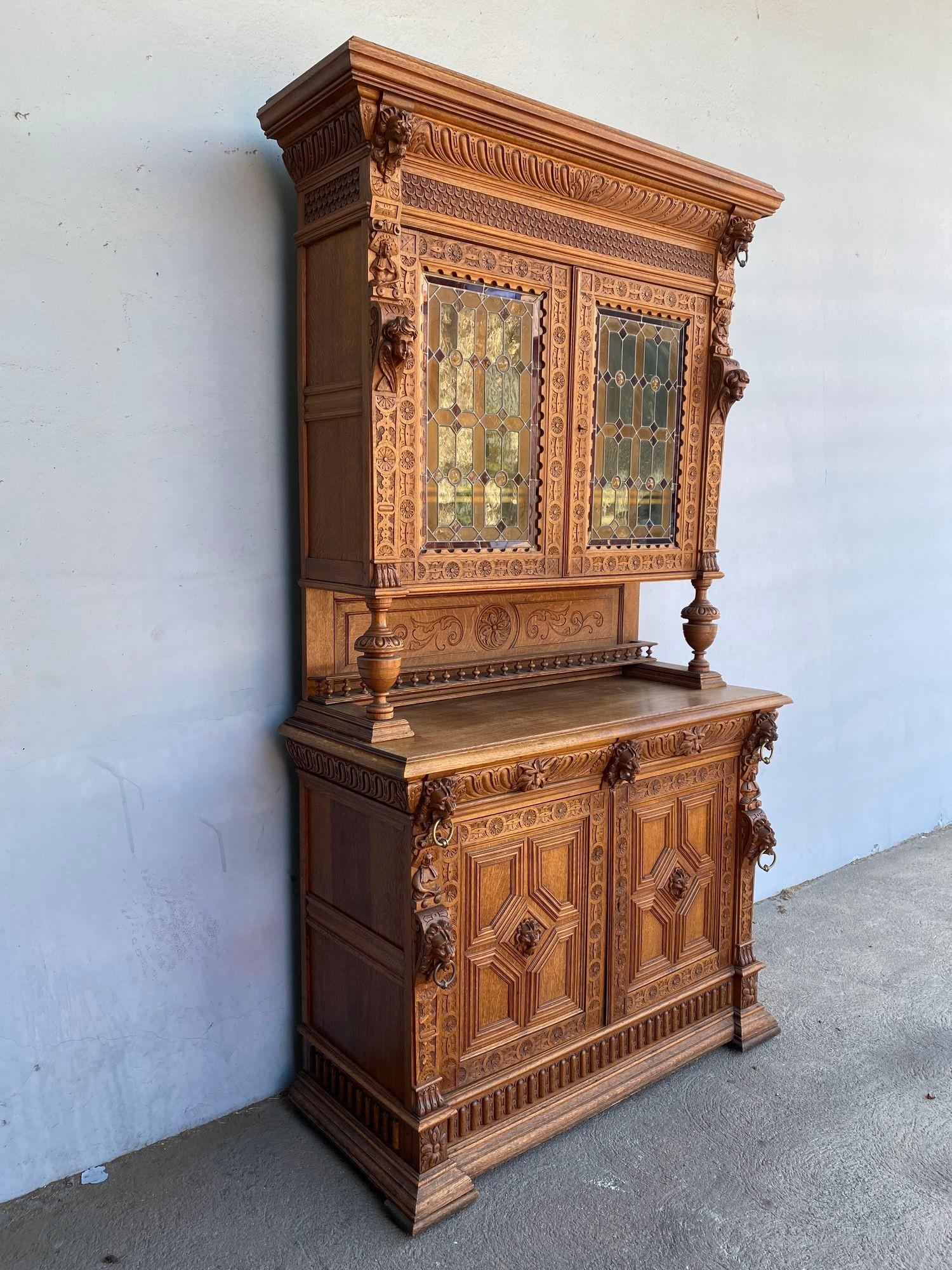 Late 19th century French Renaissance Buffet featuring hand-carved Putti angels and lion heads and large 2 staindglass doors on top. This a two-piece unit with 2 stained glass doors and 3 shelf top breakfront hutch on top. The base has two shelves