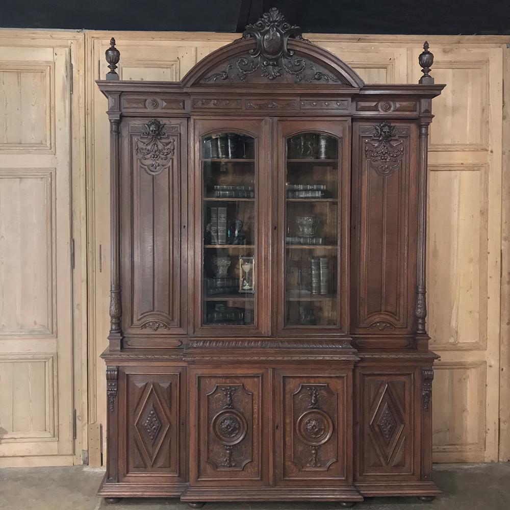 19th Century French Renaissance Grand Bookcase is a study in classical architecture rendered on a larger-than-life scale for a prominent French merchant.  The boldly arched crown is centered by an equally bold heraldic crest with descending foliates