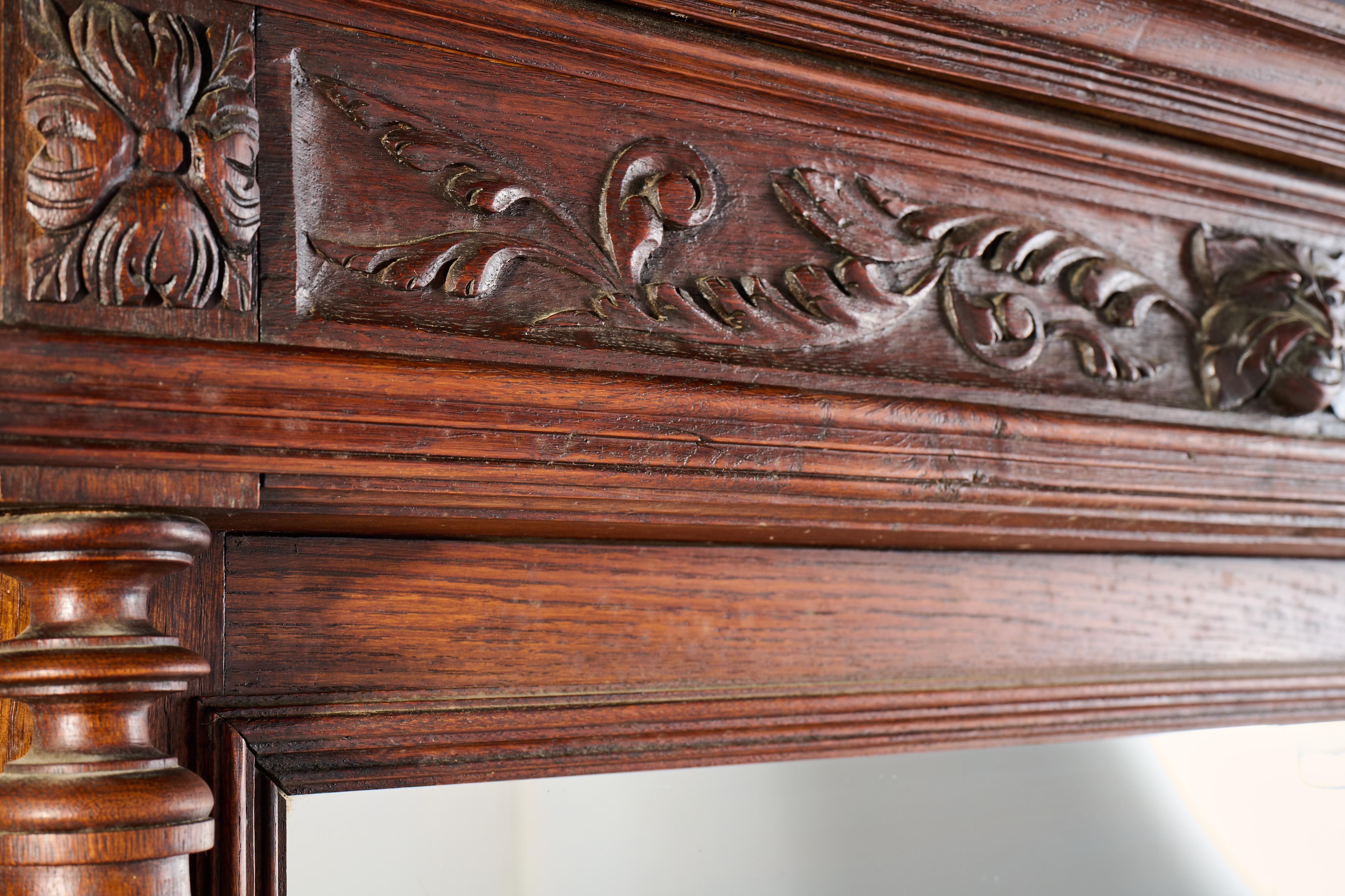 Impressionante specchio Trumeau rinascimentale francese del XIX secolo realizzato in noce riccamente patinato con dettagli architettonici di grande effetto. Risalente al 1870-1890 circa, lo specchio presenta un fregio profondamente intagliato con