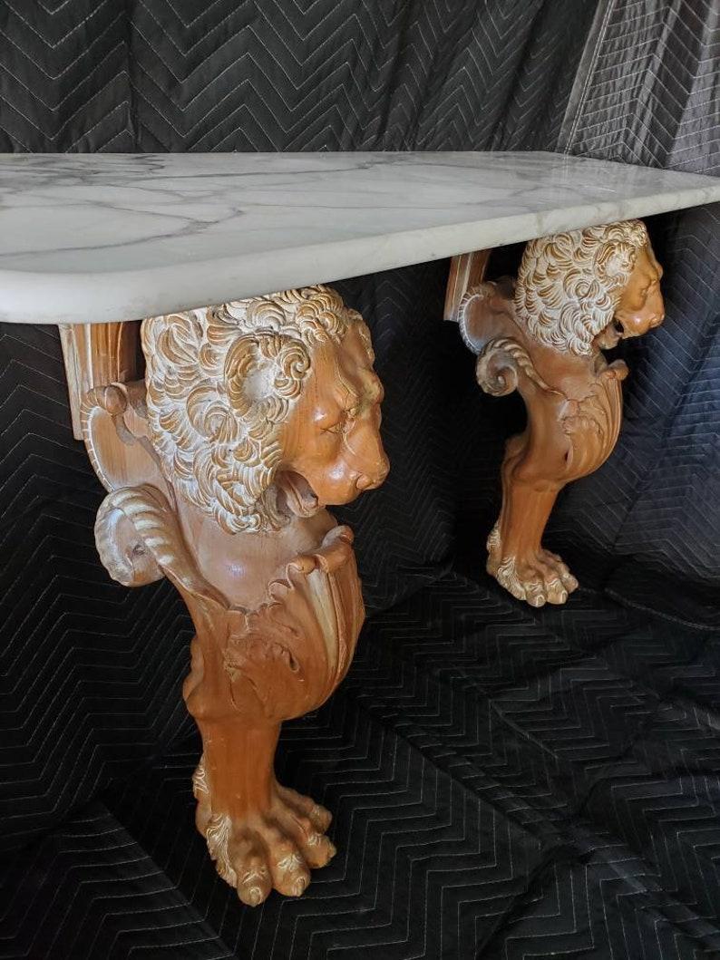 A hand carved French Renaissance Revival marble-top figural console table from the late 19th c., having marble top with curved corners, above heavily carved wood base featuring lion figures, ending in paw feet.

Dimensions (approx): 
30.75