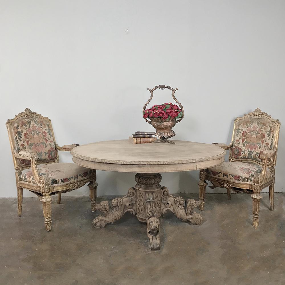 19th century French Renaissance stripped oak center table with hunting dogs features a different sculpture of a hunting dog on each of the four elegantly scrolled legs that support the massive hand carved center pedestal which in turn supports the